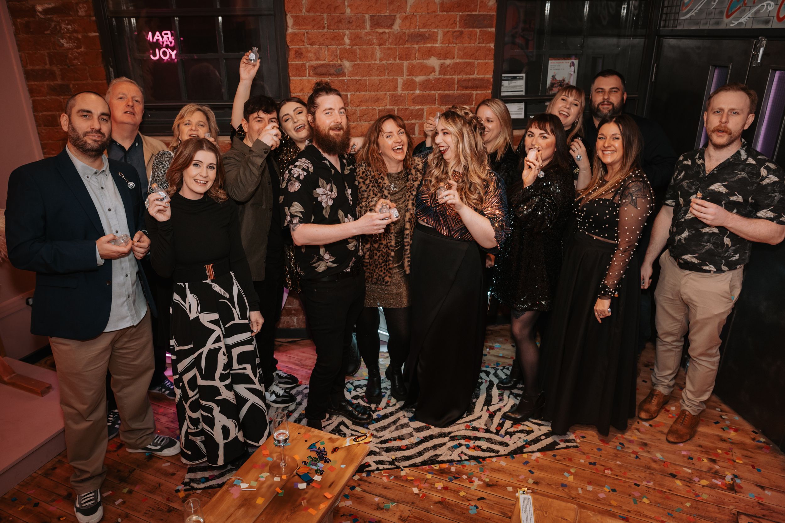 A group photo of people in formal attire at a brick-walled venue.