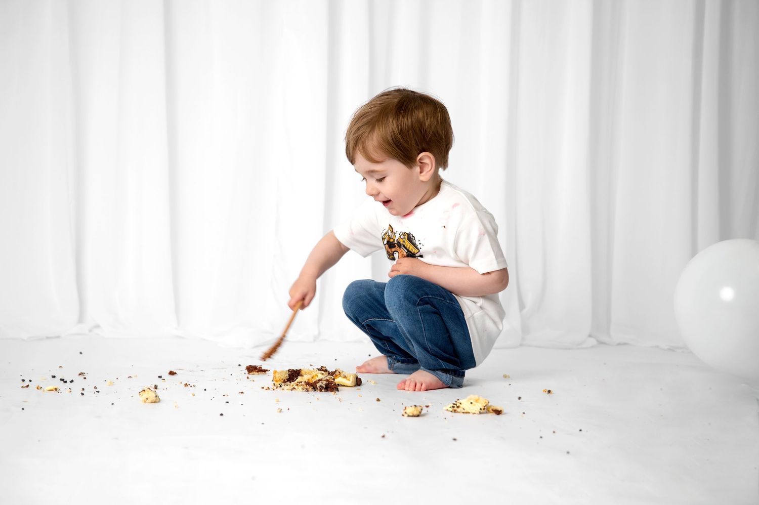 A panoramic sequence shows a child in white crawling along a white surface while playing with scattered toys and candies.
