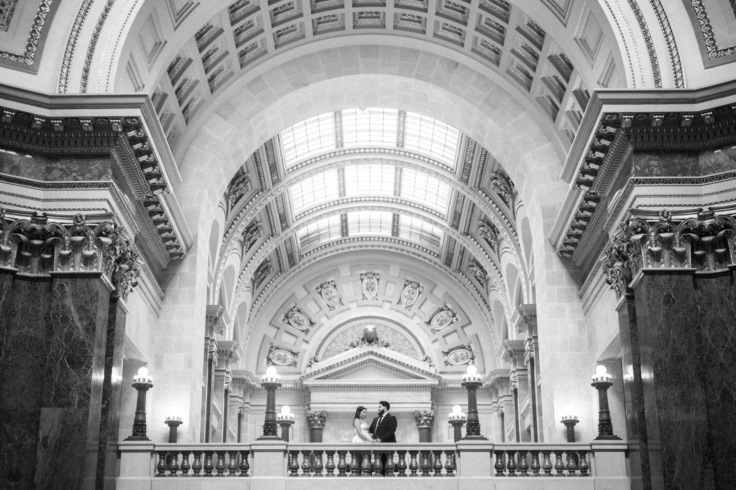 Black and white architectural photograph of an ornate arched ceiling with marble columns in a grand historic building.