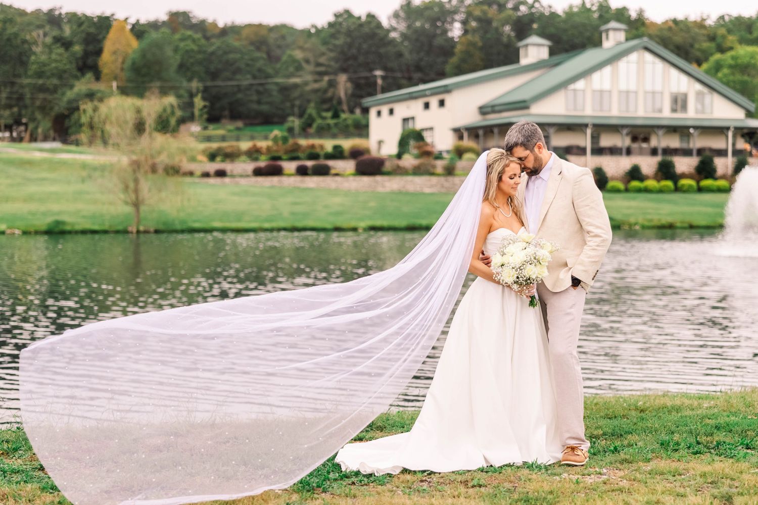 Wedding portraits by a serene lake with a flowing white dress and natural scenery.