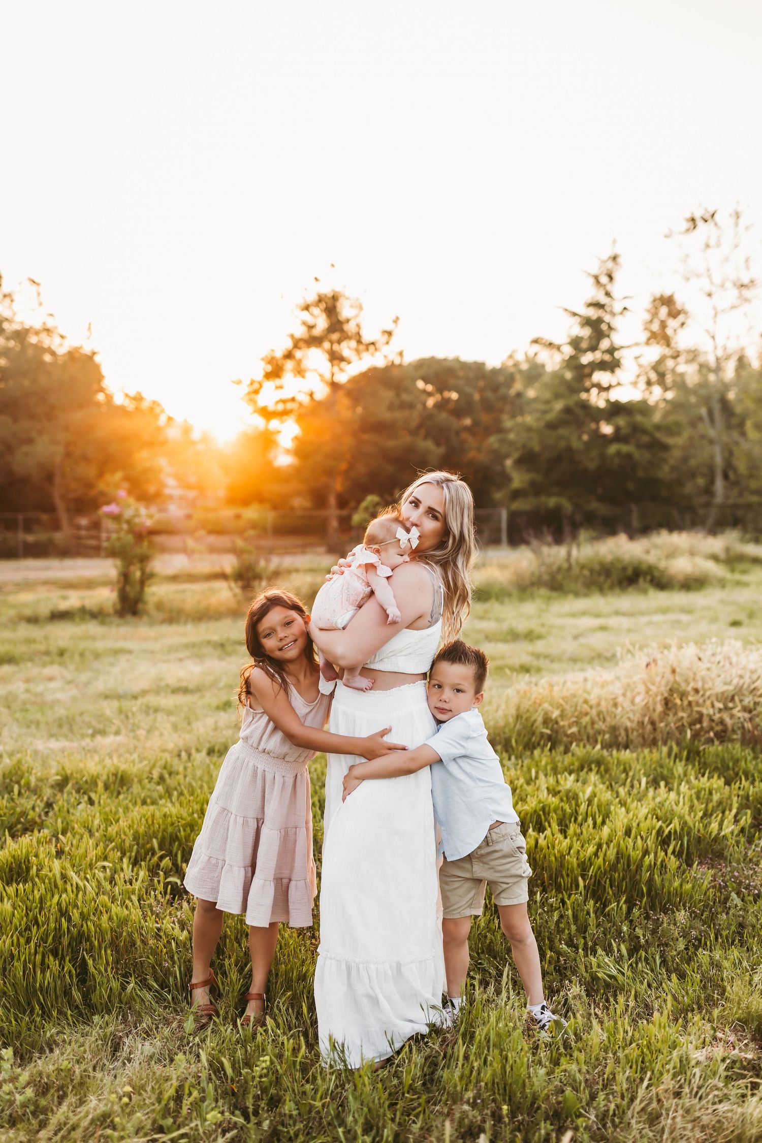 Family shares joyful moment together in sun-drenched field at golden hour.