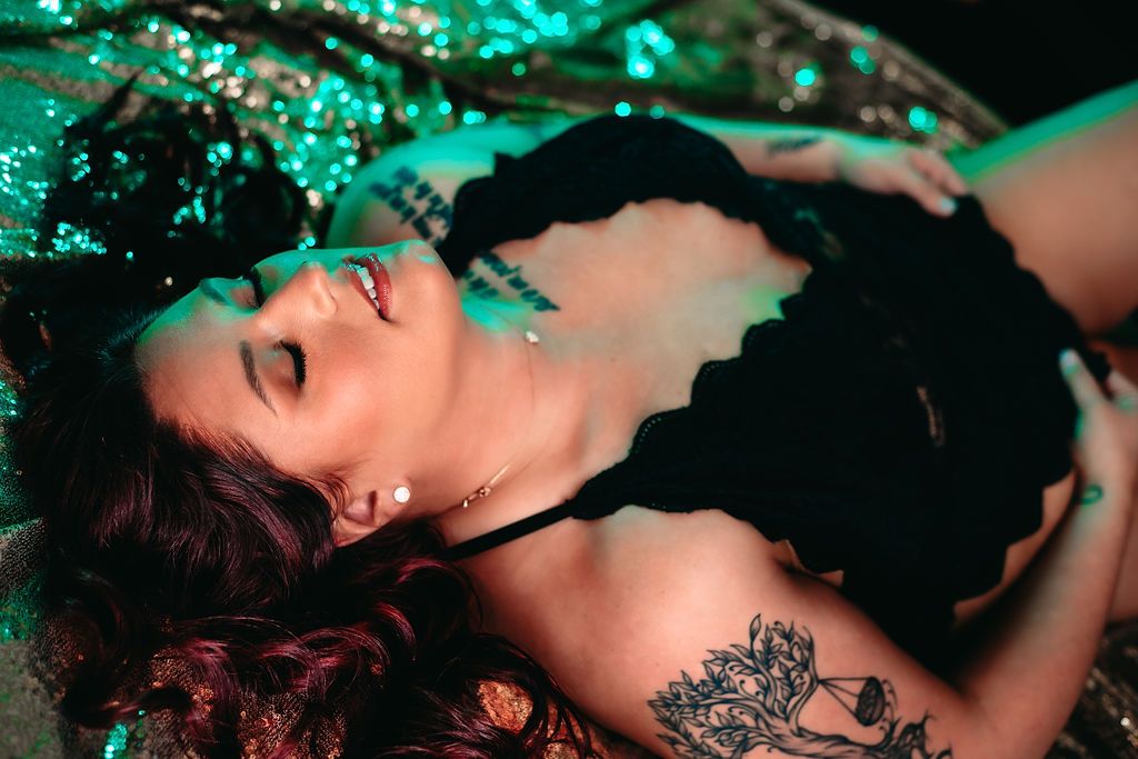 Artistic boudoir photo with emerald lighting and dark lace details.