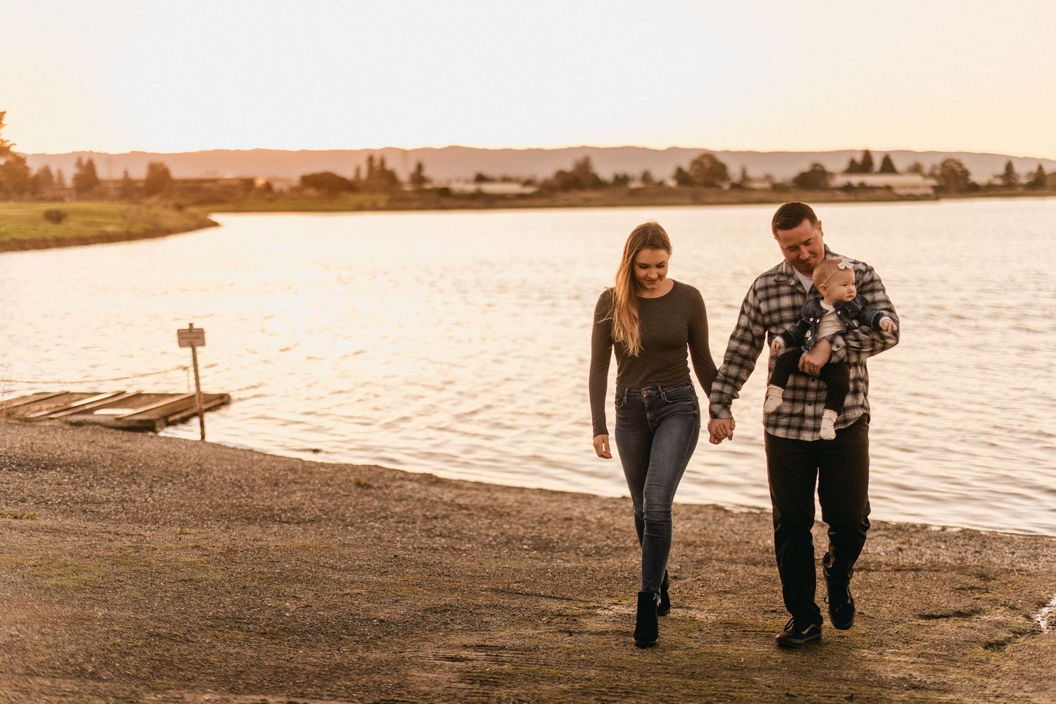 A couple takes a sunset walk along a waterfront path.