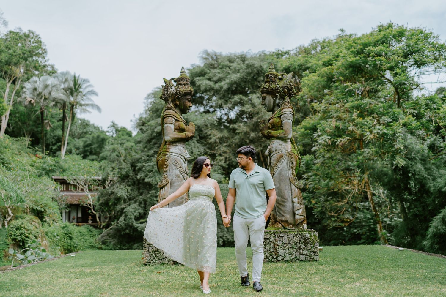 Couple walking along a green garden pathway surrounded by tropical plants.