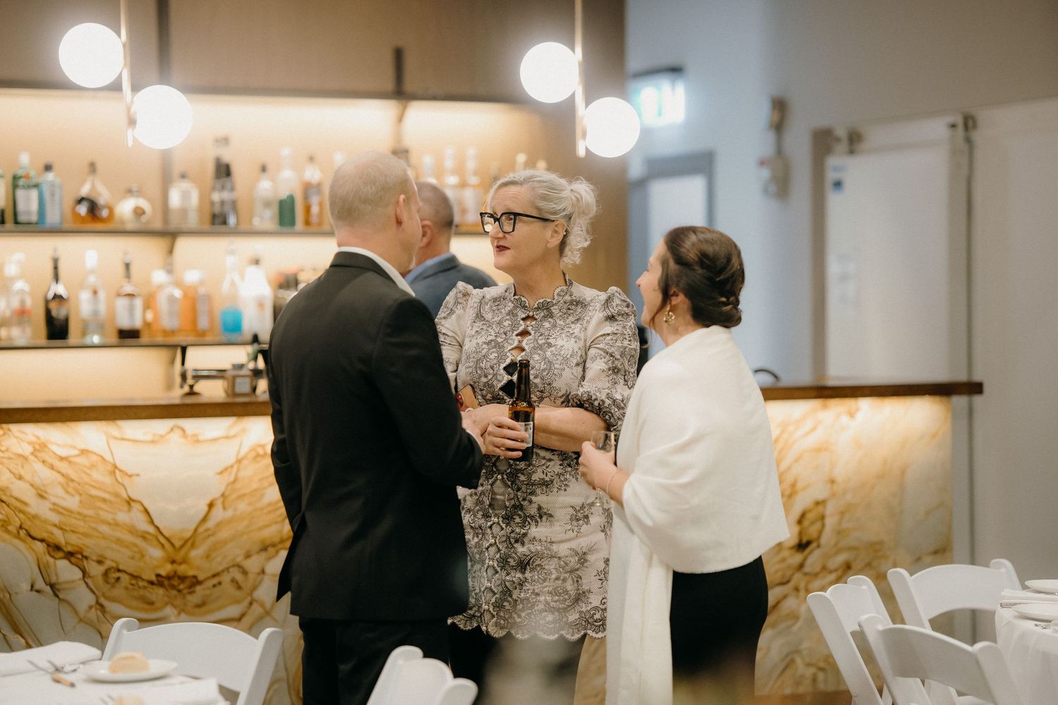 Business professionals networking at a corporate event, reviewing documents and smartphones in a modern office setting.