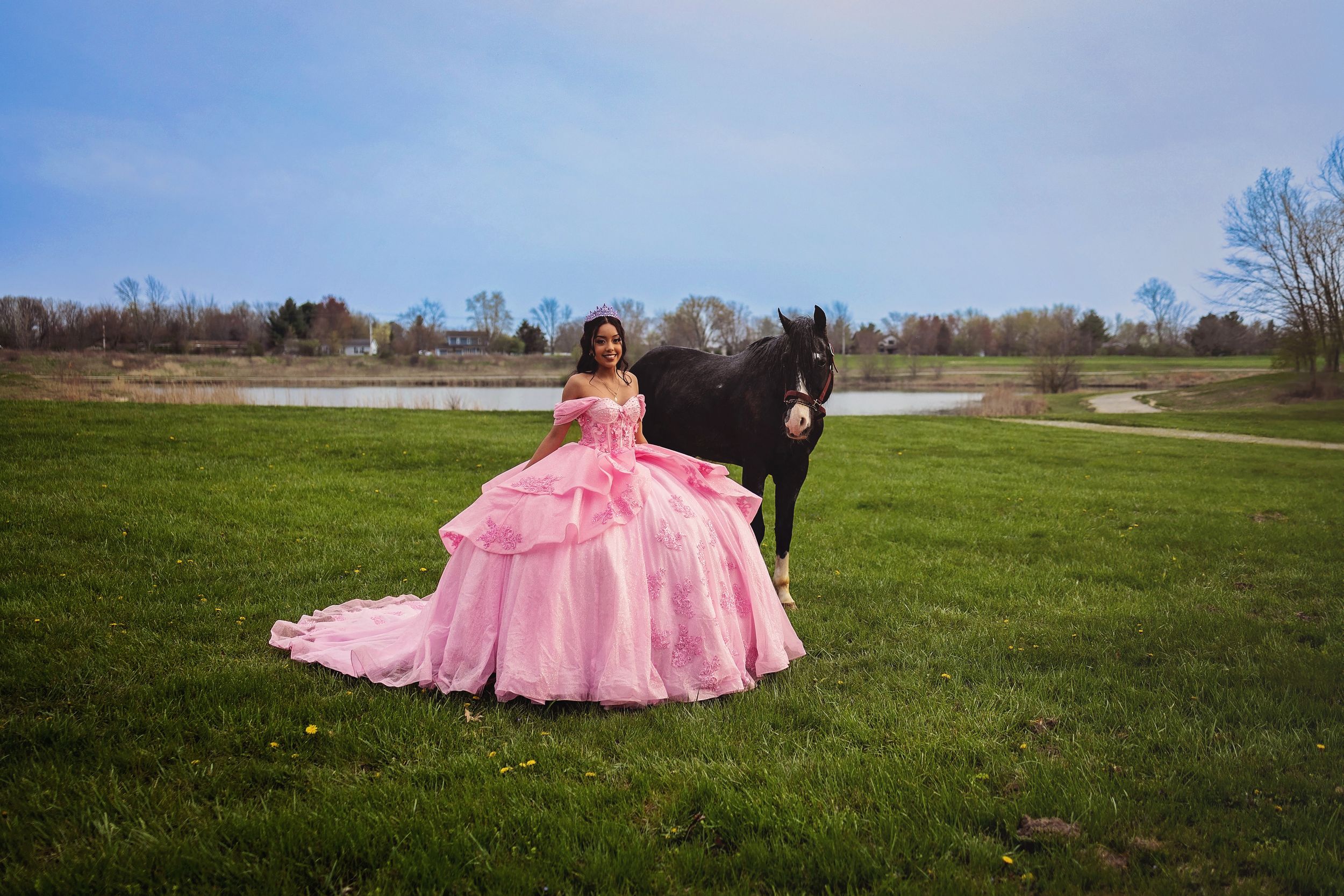A flowing pink princess gown stands out against a scenic lake backdrop.
