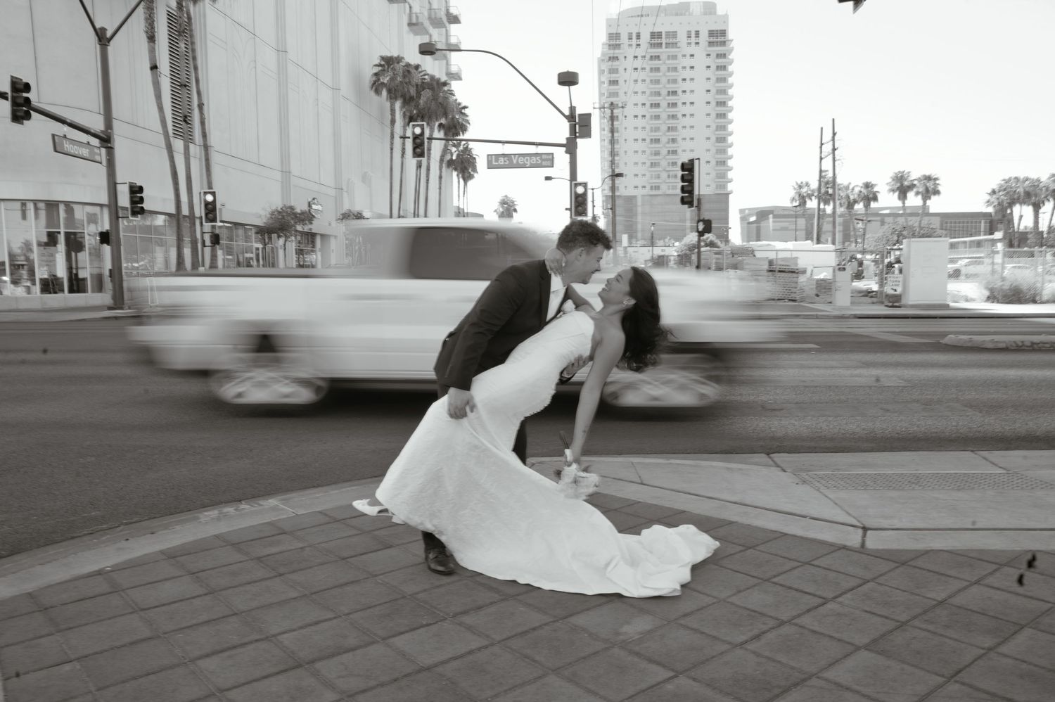 Bride and groom pose elegantly in a grand marble colonnade, her white ball gown trailing gracefully on the ornate floor.