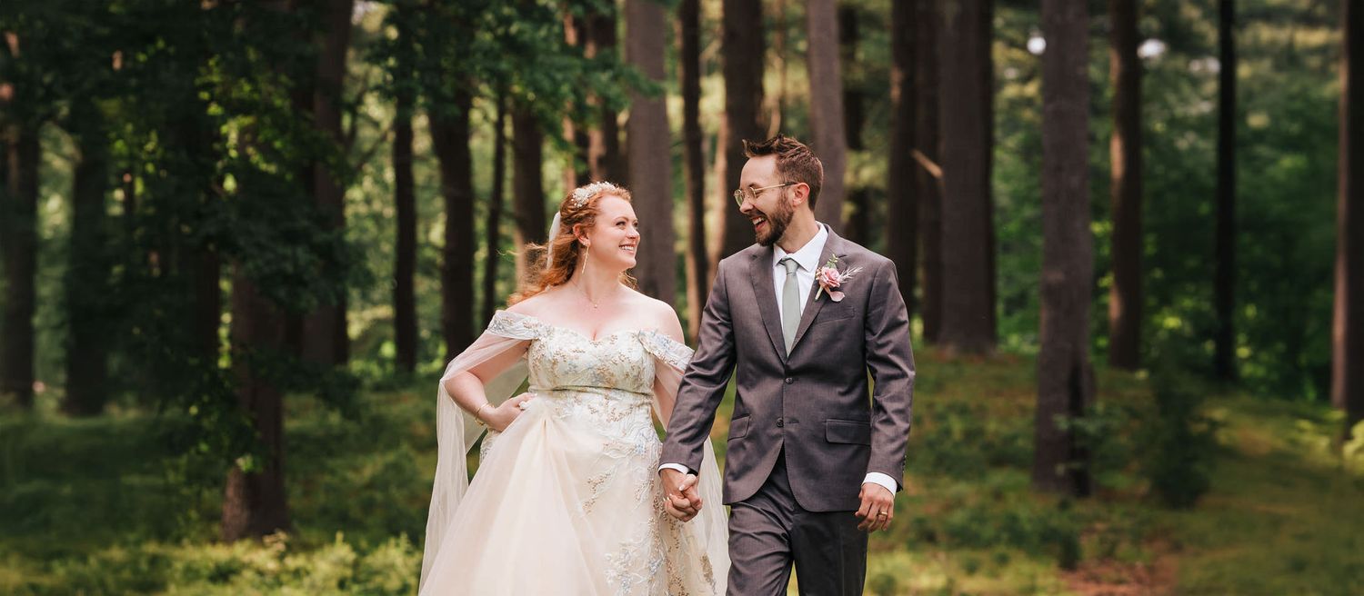 Bride and groom laughing in a wooded clearing near Searles Castle in Windham, NH, during romantic portraits after their carriage ride.