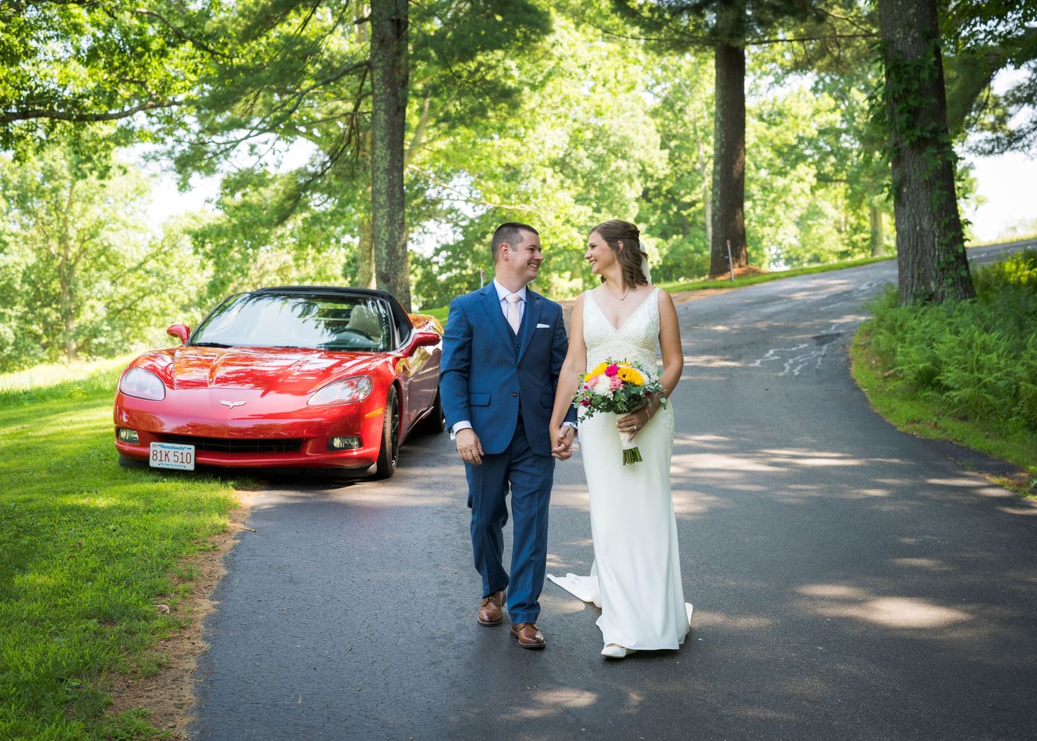 Newlyweds share an intimate moment outdoors with autumn foliage and rustic architecture in background.