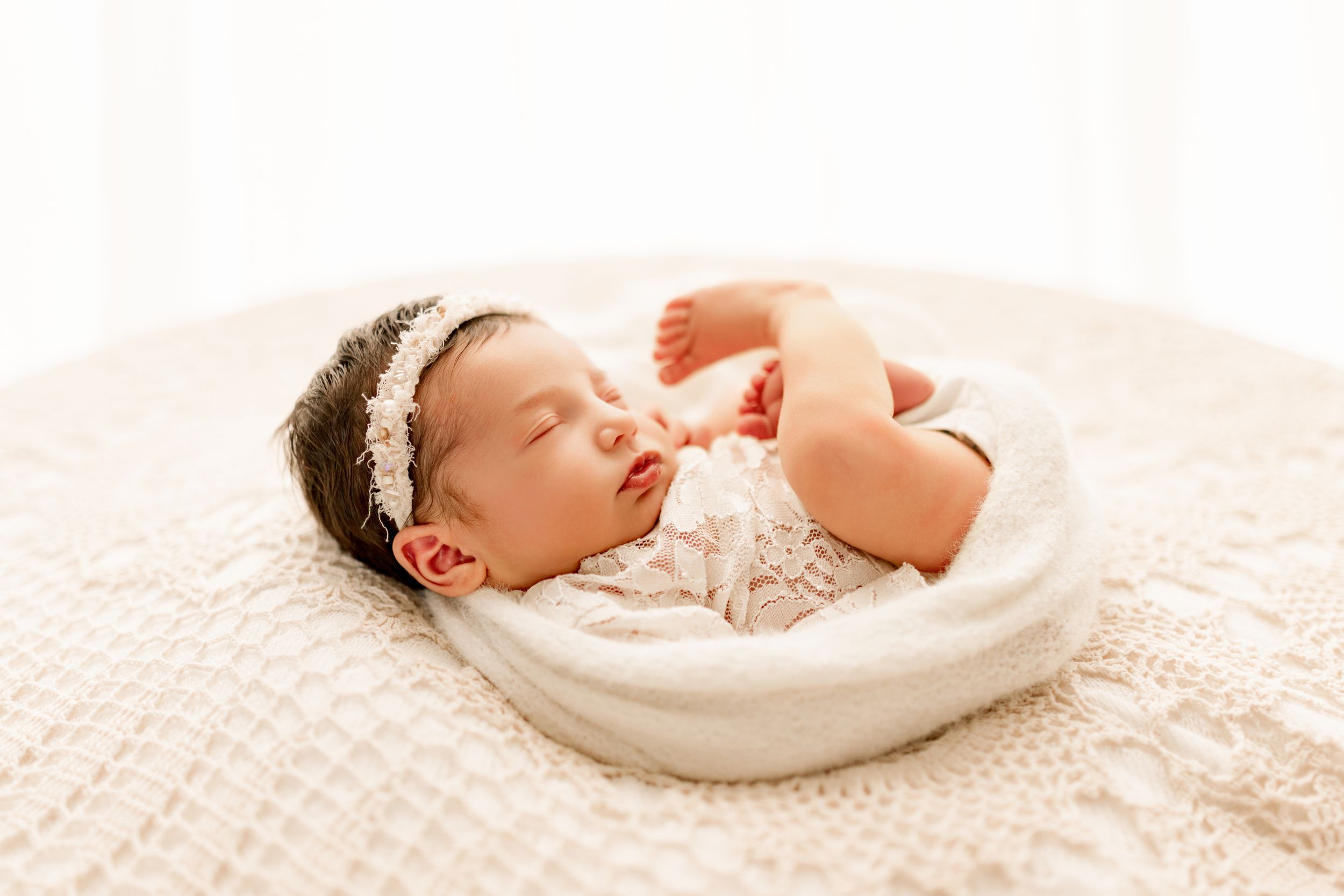Lifestyle Baby girl wearing white and creams wrapped up during Newborn photo session  in Marion, Indiana