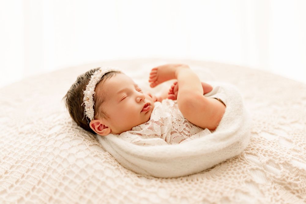 Lifestyle Baby girl wearing white and creams wrapped up during Newborn photo session  in Marion, Indiana
