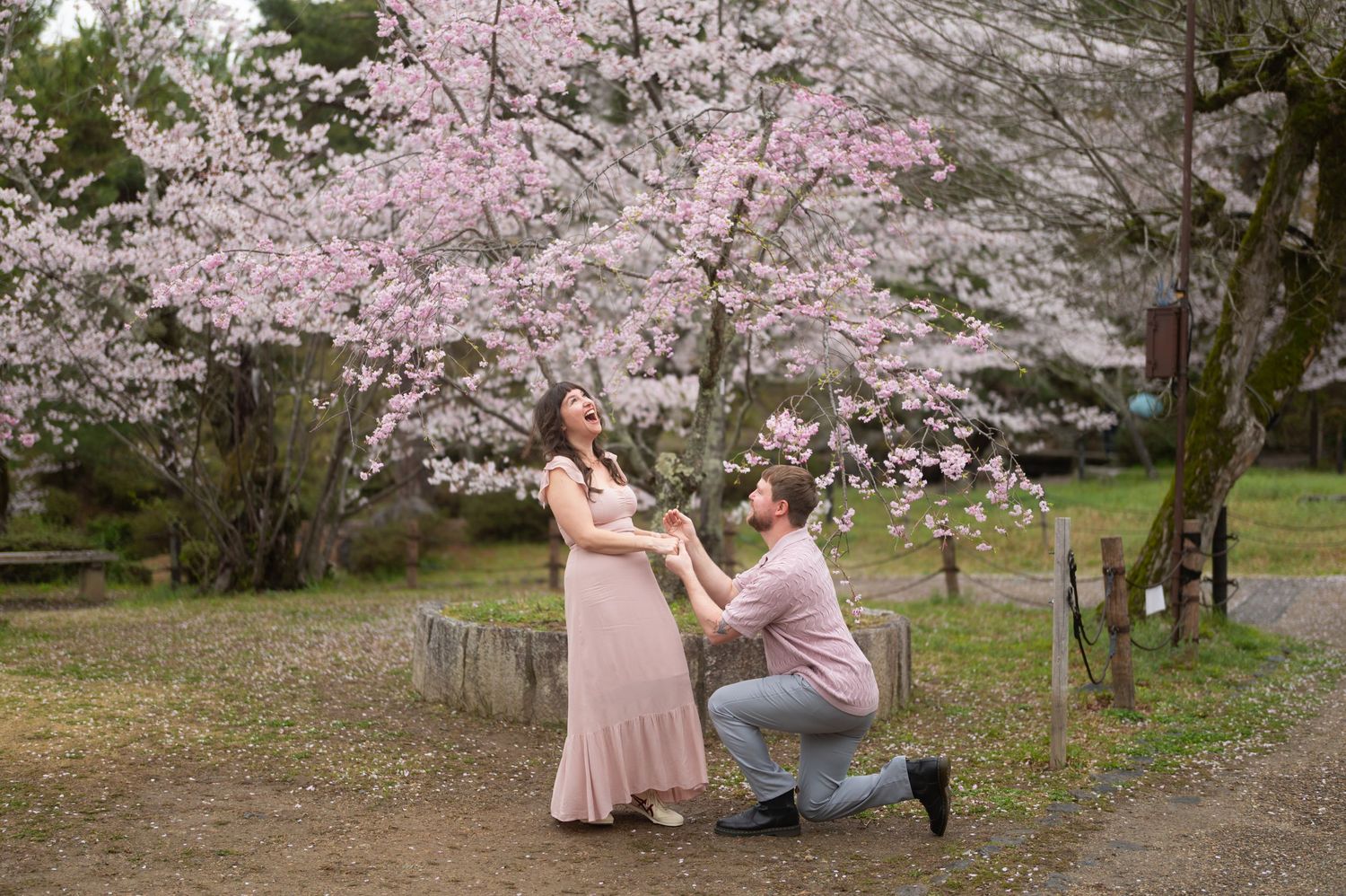 Couple standing together in a traditional Japanese garden with a historic pagoda-style building in the background.