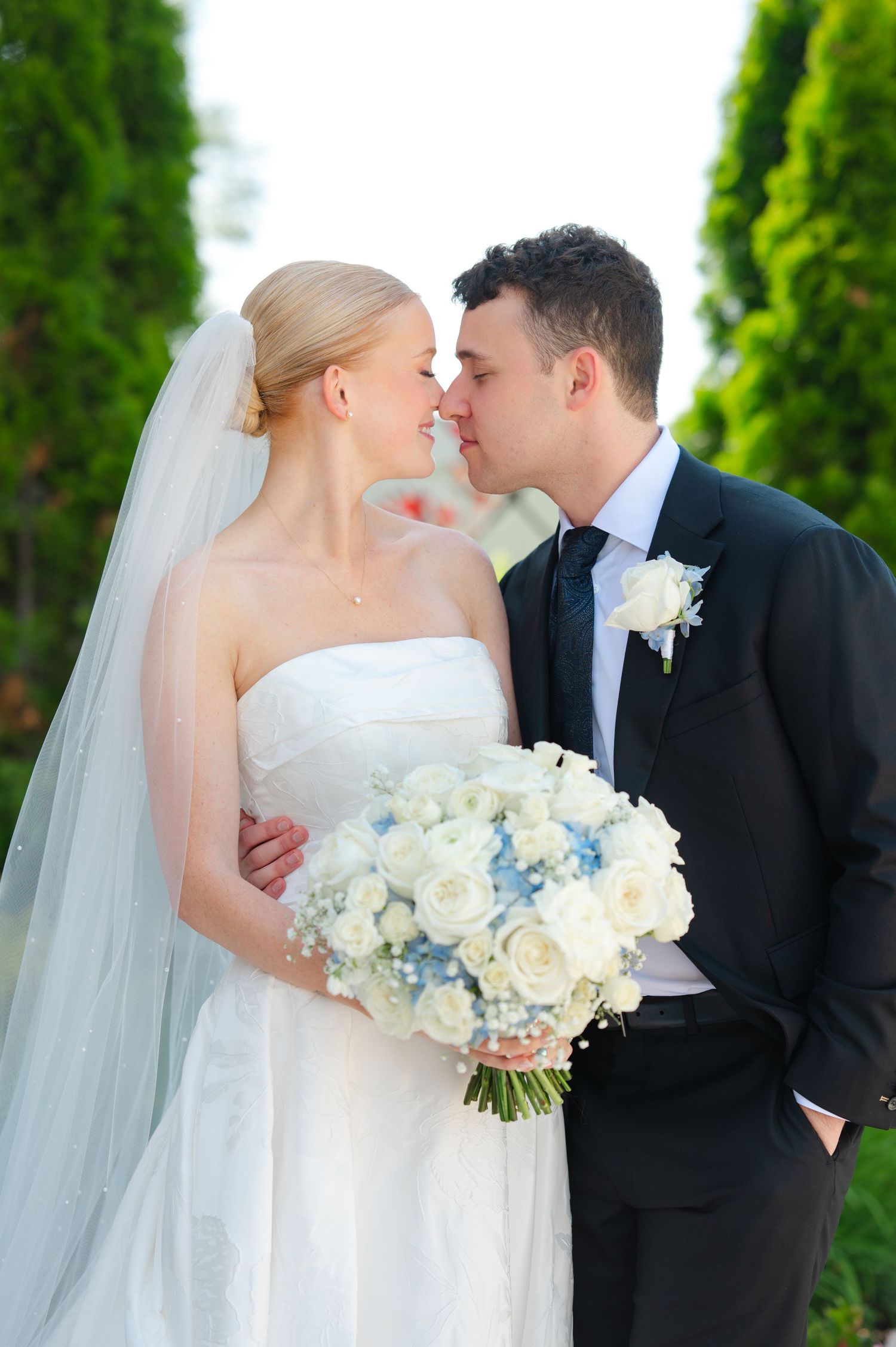 A bride and groom share a tender moment, smiling at each other during their wedding ceremony outdoors.