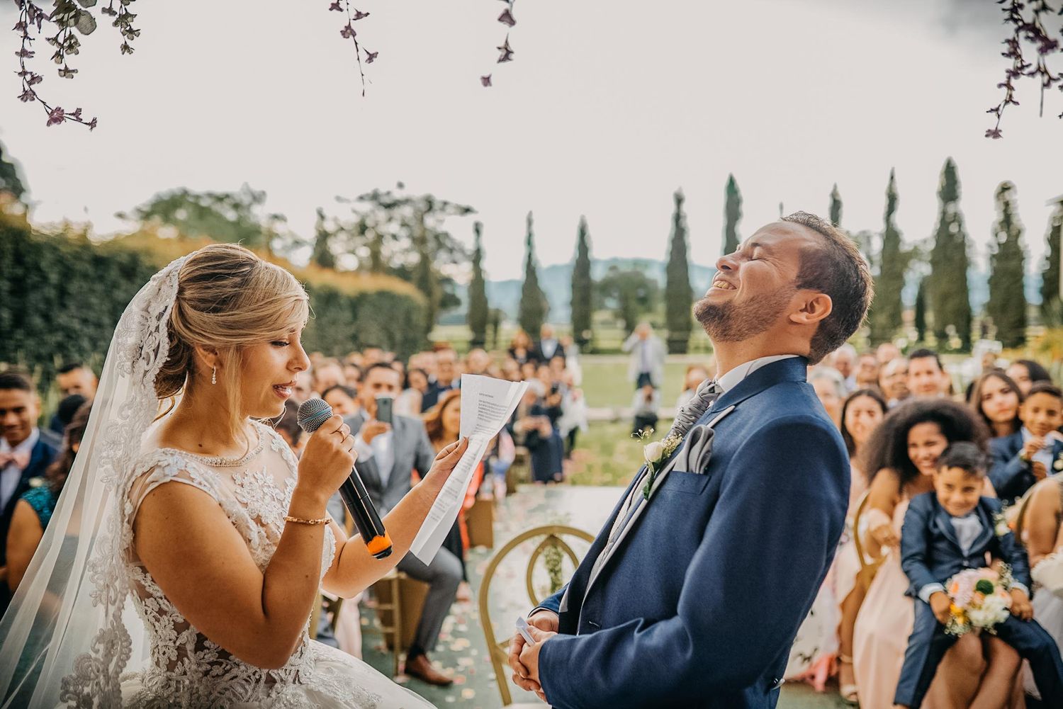 Bride and groom share romantic moment by stained glass windows in golden light, bride in elegant ballgown with long veil.