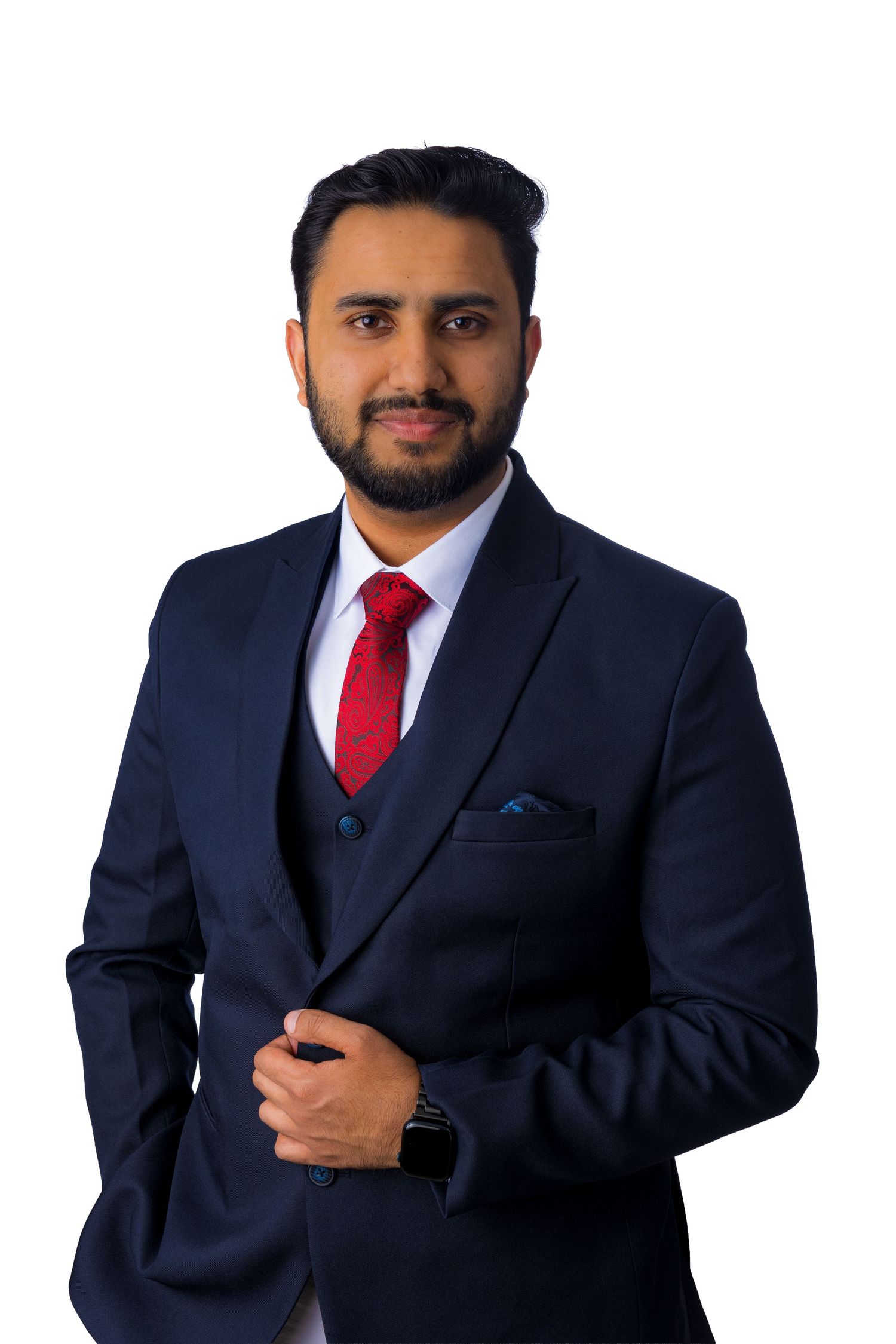 Professional man in navy blue three-piece suit with red tie posing confidently against white background.