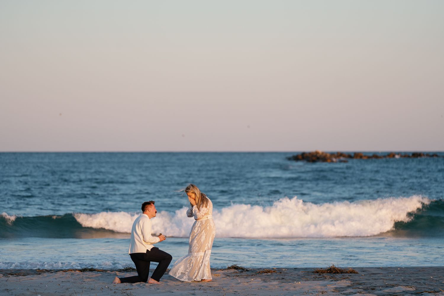 Man proposes to woman on a beach at sunset, kneeling with ring. Wrightsville Beach, NC Photographer - Wilmington NC Wedding Photography