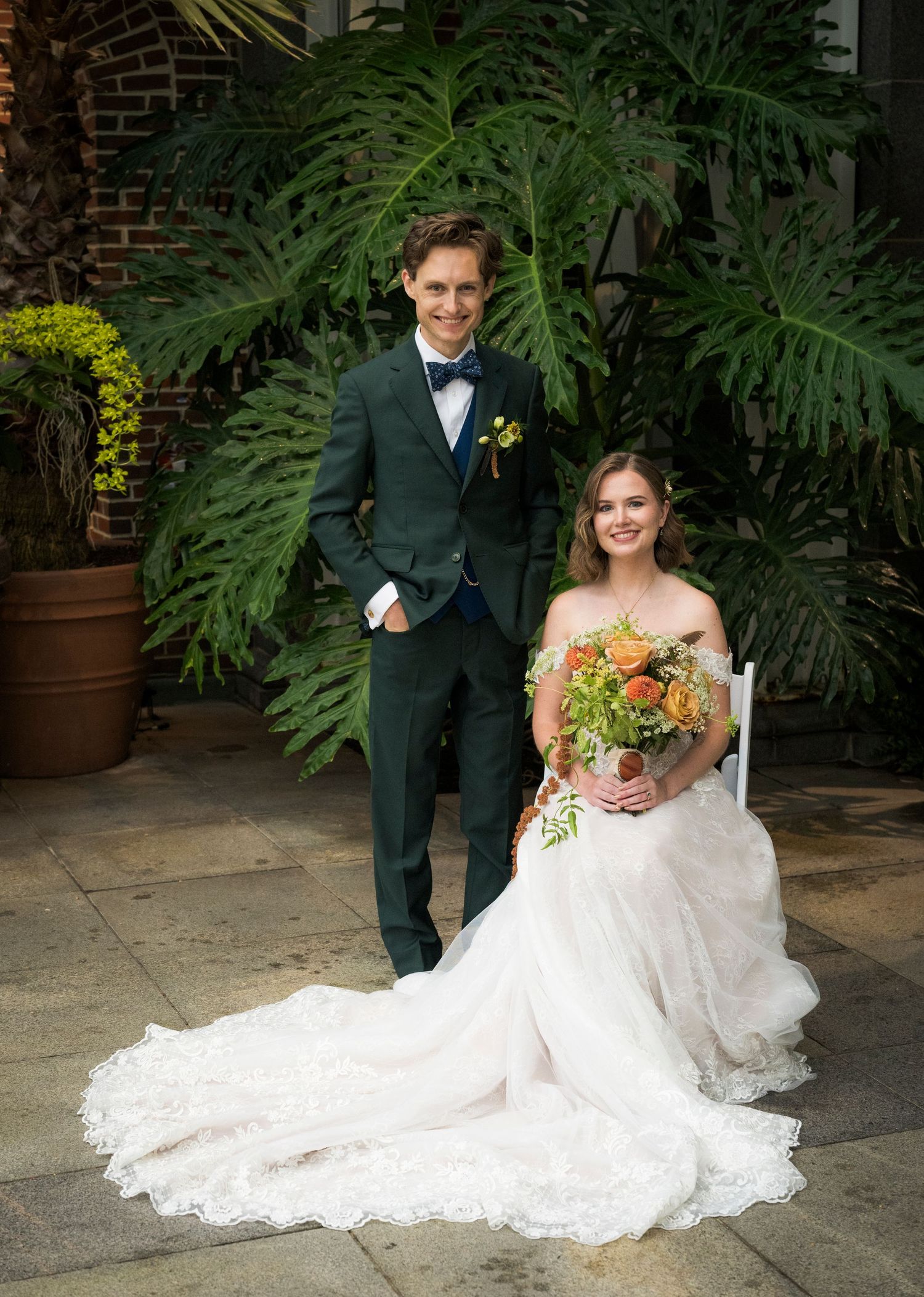 Romantic wedding couple poses in a spring garden with hanging white decorative spheres.