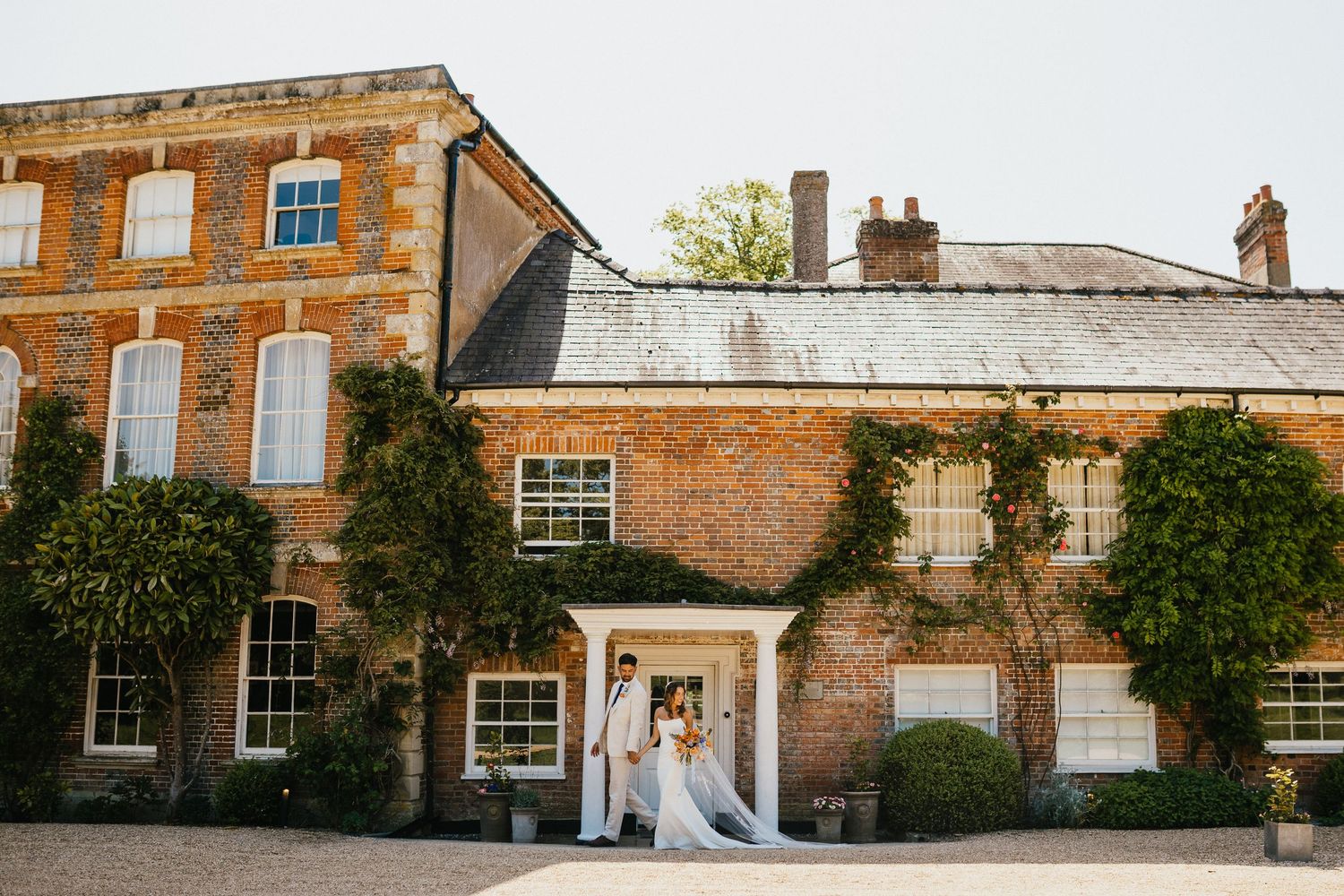 Bride and groom portraits, walking infront of the house at Syrencot wedding venue in Wiltshire