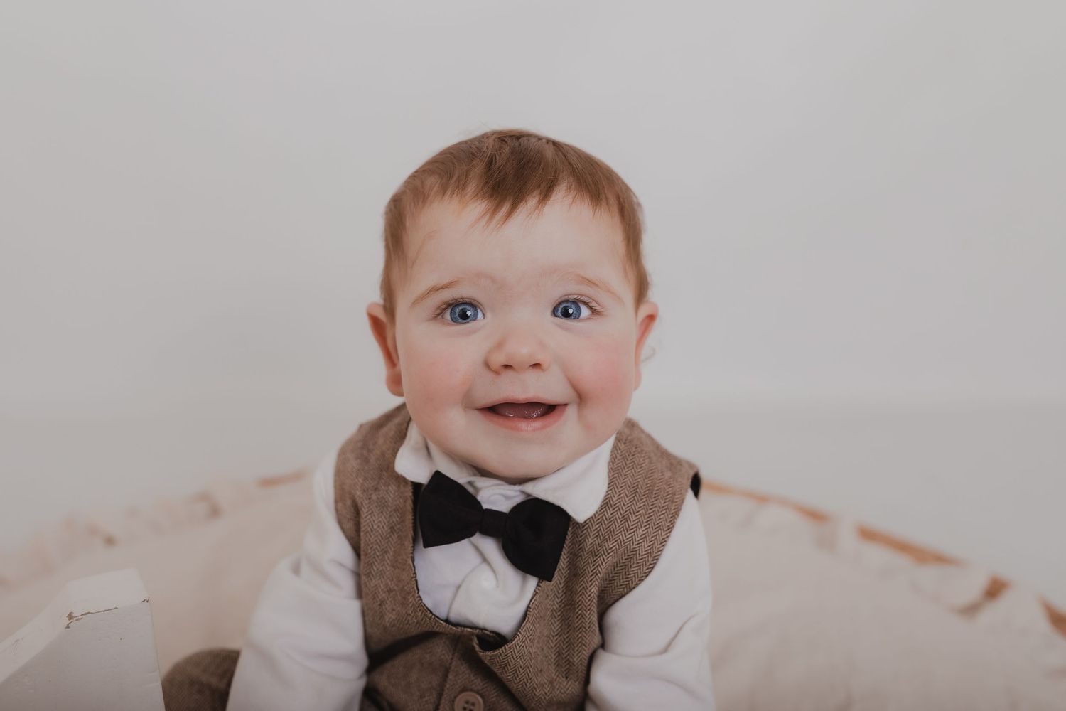 Baby wearing formal brown vest and bowtie smiling during portrait session. Photographer. Hull. East Yorkshire. Photography