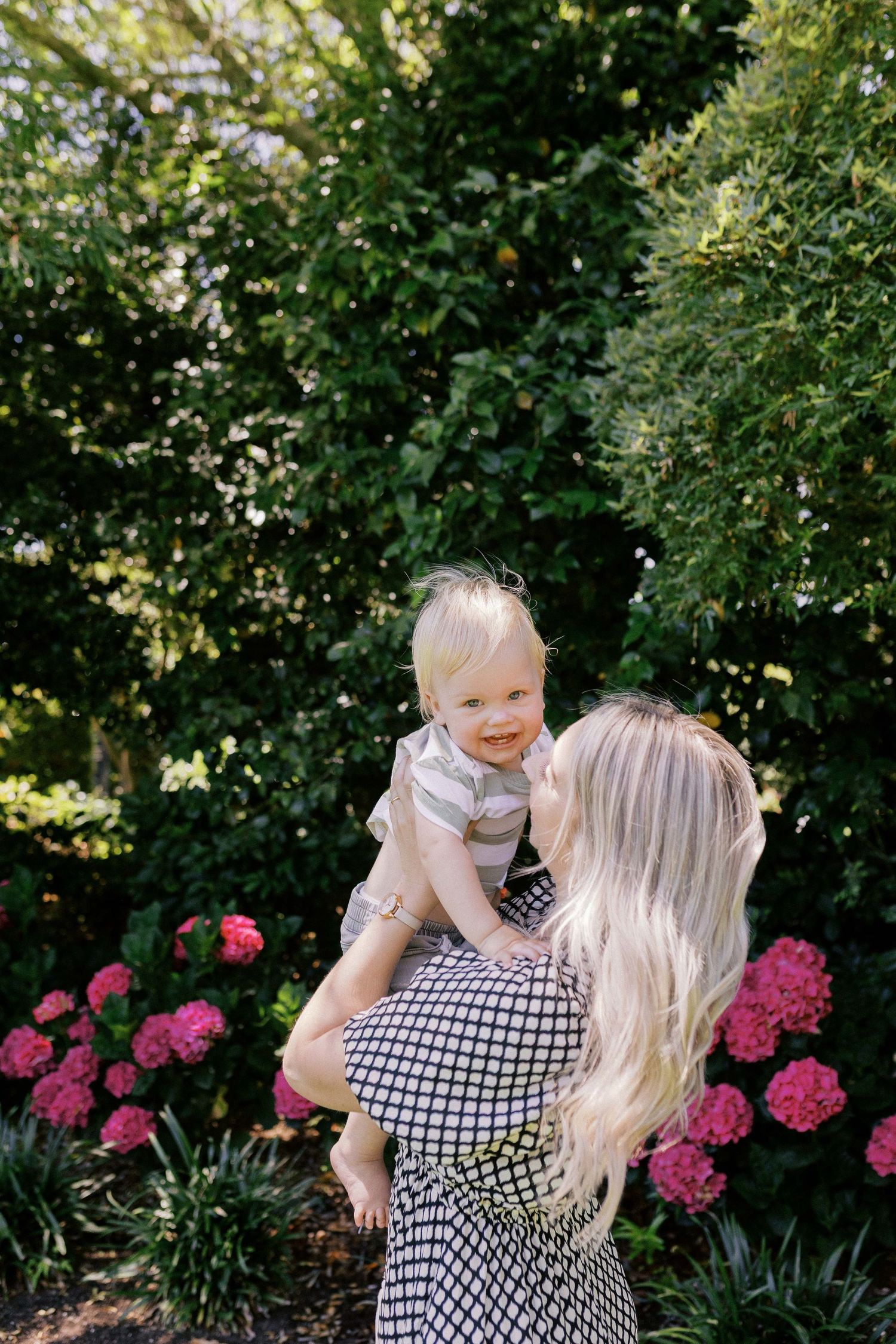 A joyful moment shared in a garden with blooming pink hydrangeas and lush greenery in the background.