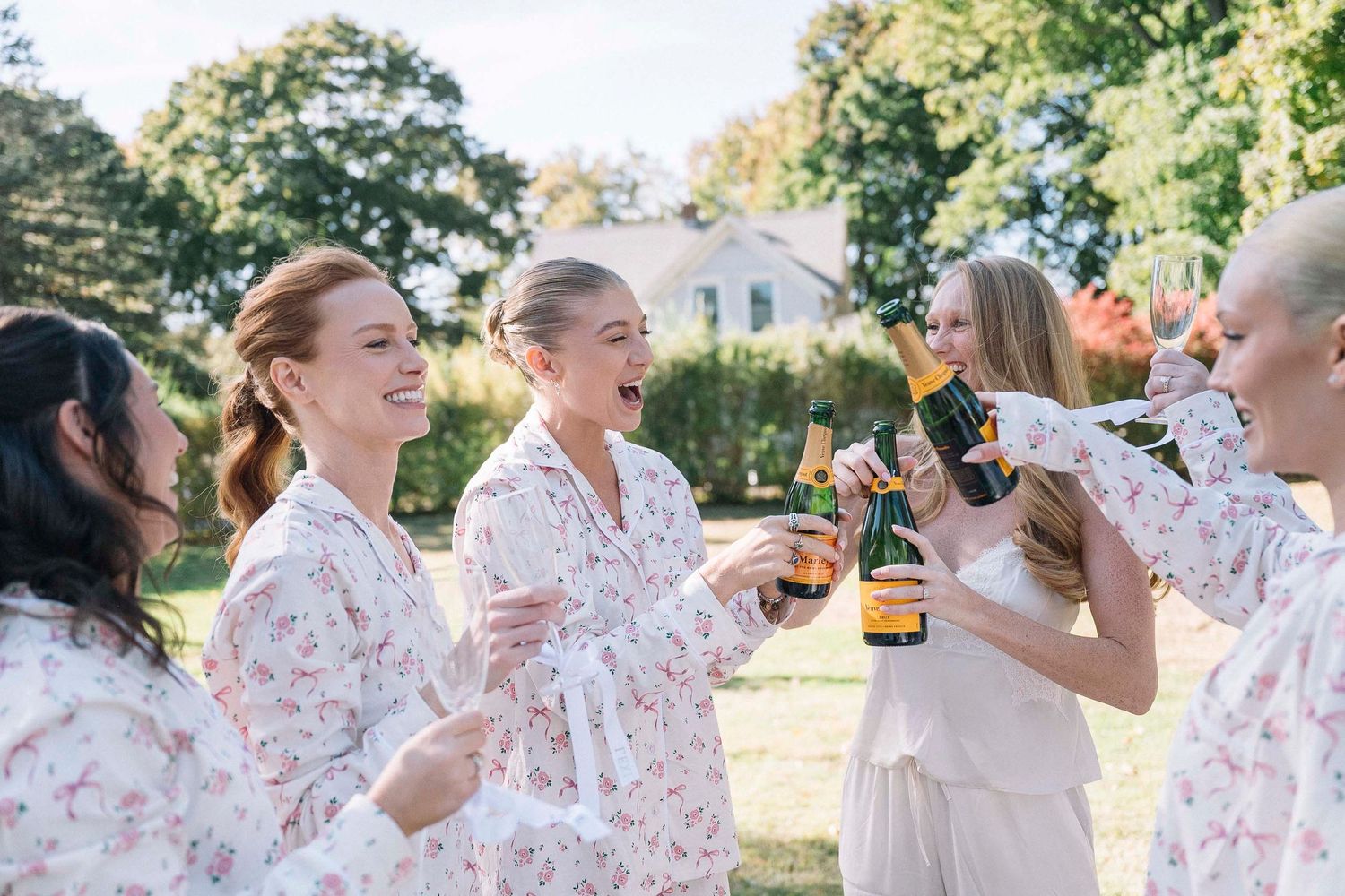 Wedding party celebrates joyfully while walking along a scenic waterfront dock on a beautiful sunny day at Essex Yacht Club. Anaise Prince