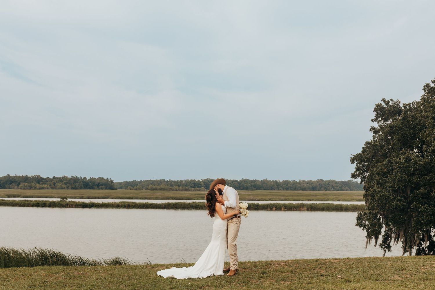 A romantic wedding couple on a scenic beach dock and marsh boardwalk during golden hour.