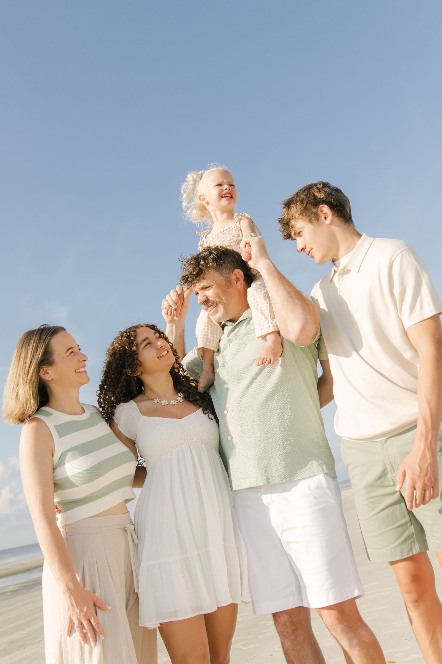 Close-up editorial shot and camera angle of a family cuddling together during a beach photography session in the Golden Isles.