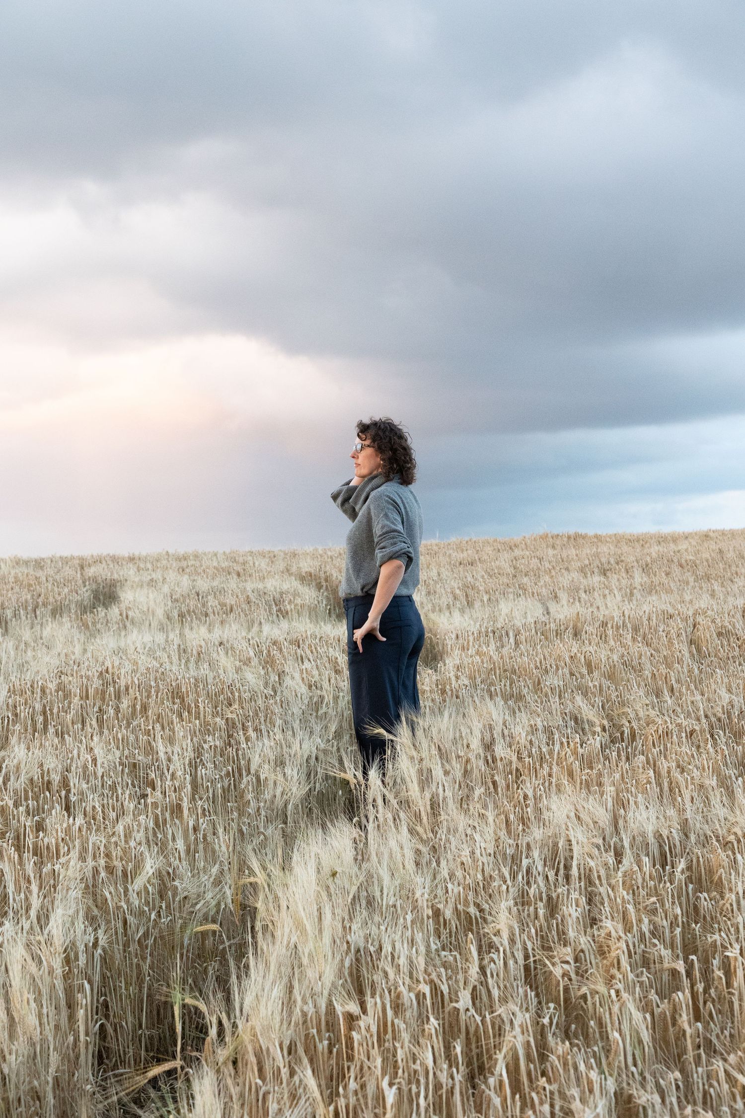 Joanne looking into the distance while standing in a hayfield.