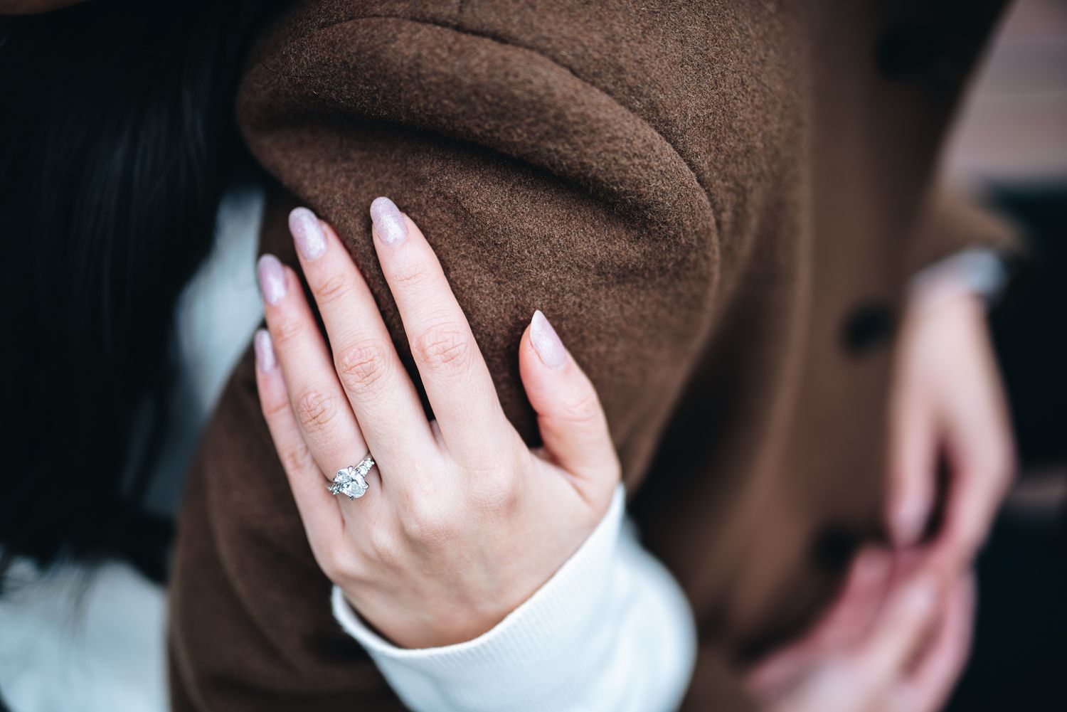 Close-up of a hand with pale pink manicure wearing an engagement ring during a Melbourne engagement photo session.
