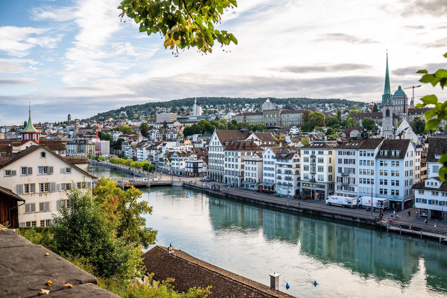 Scenic cityscape view of Zurich with Limmat River, historic buildings and church spires under blue sky.