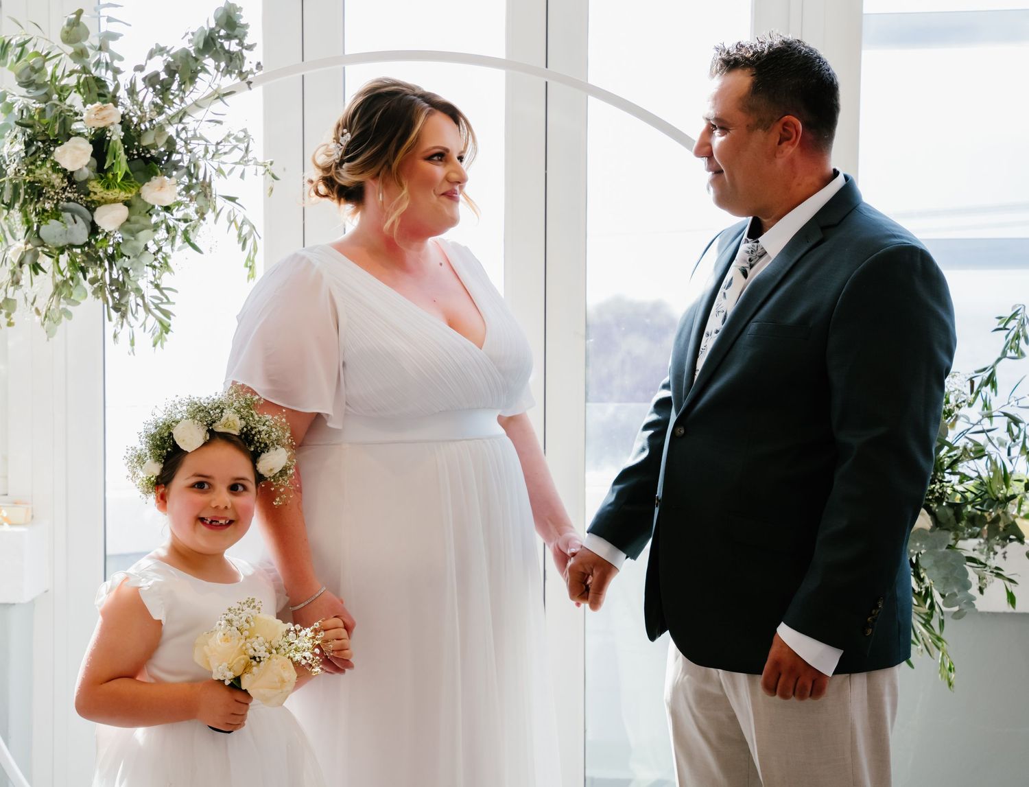 A series of elegant white wedding photos showing intimate moments between the couple against bright window lighting.