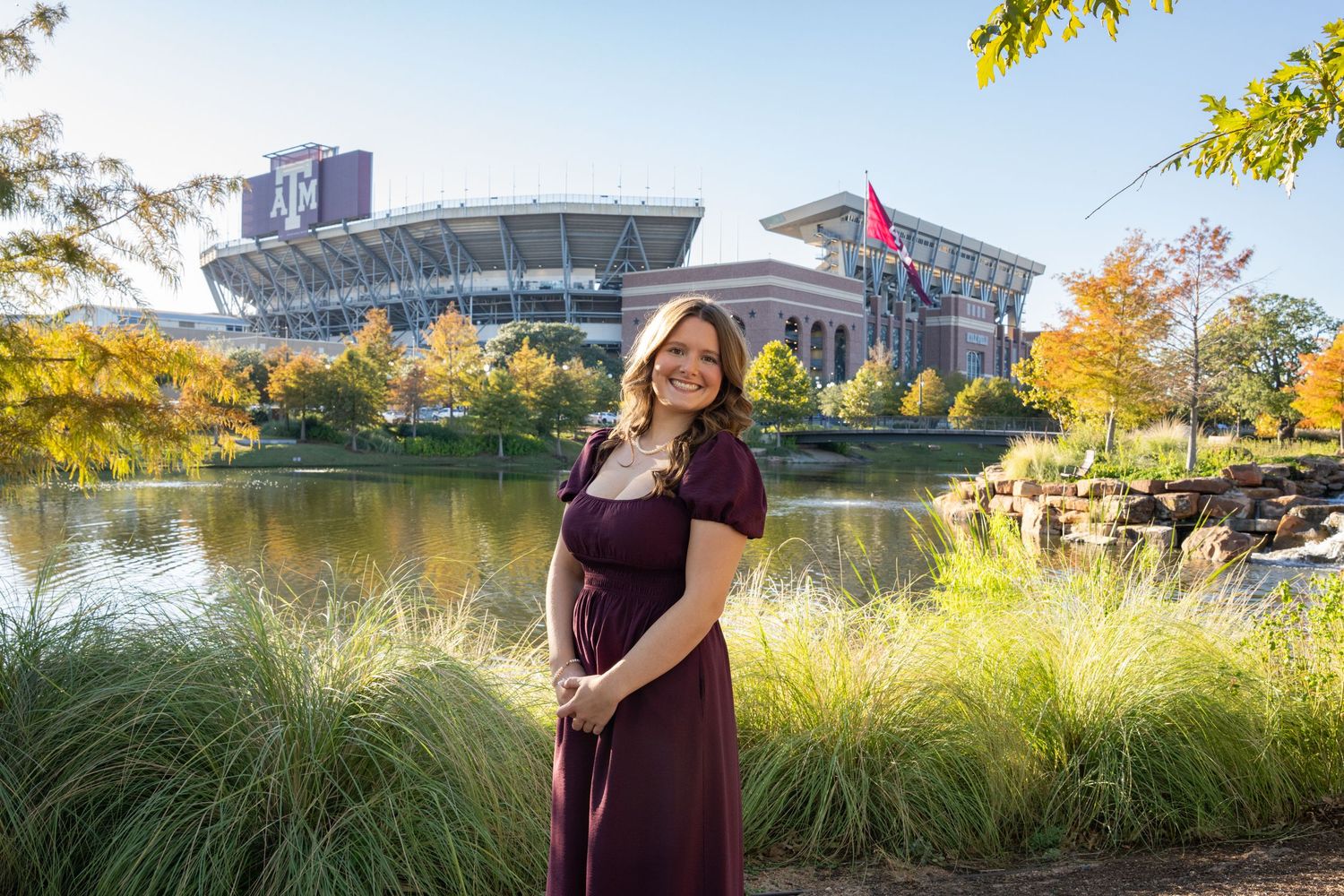 A scenic lakeside engagement photo session with fall foliage and a bridge in the background.