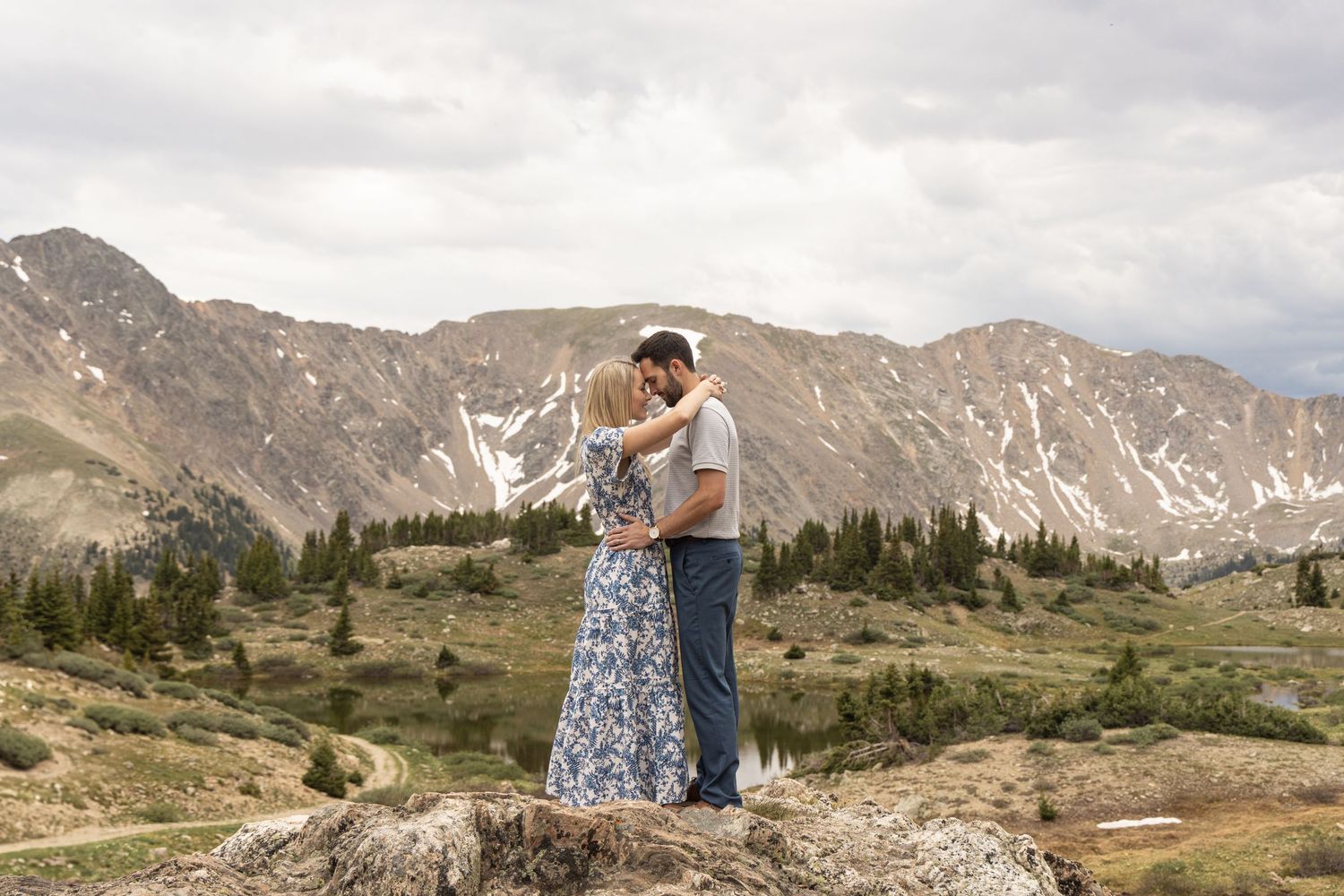 Couple embracing and viewing scenic mountain landscapes during a summer engagement photoshoot in the Colorado Rockies.