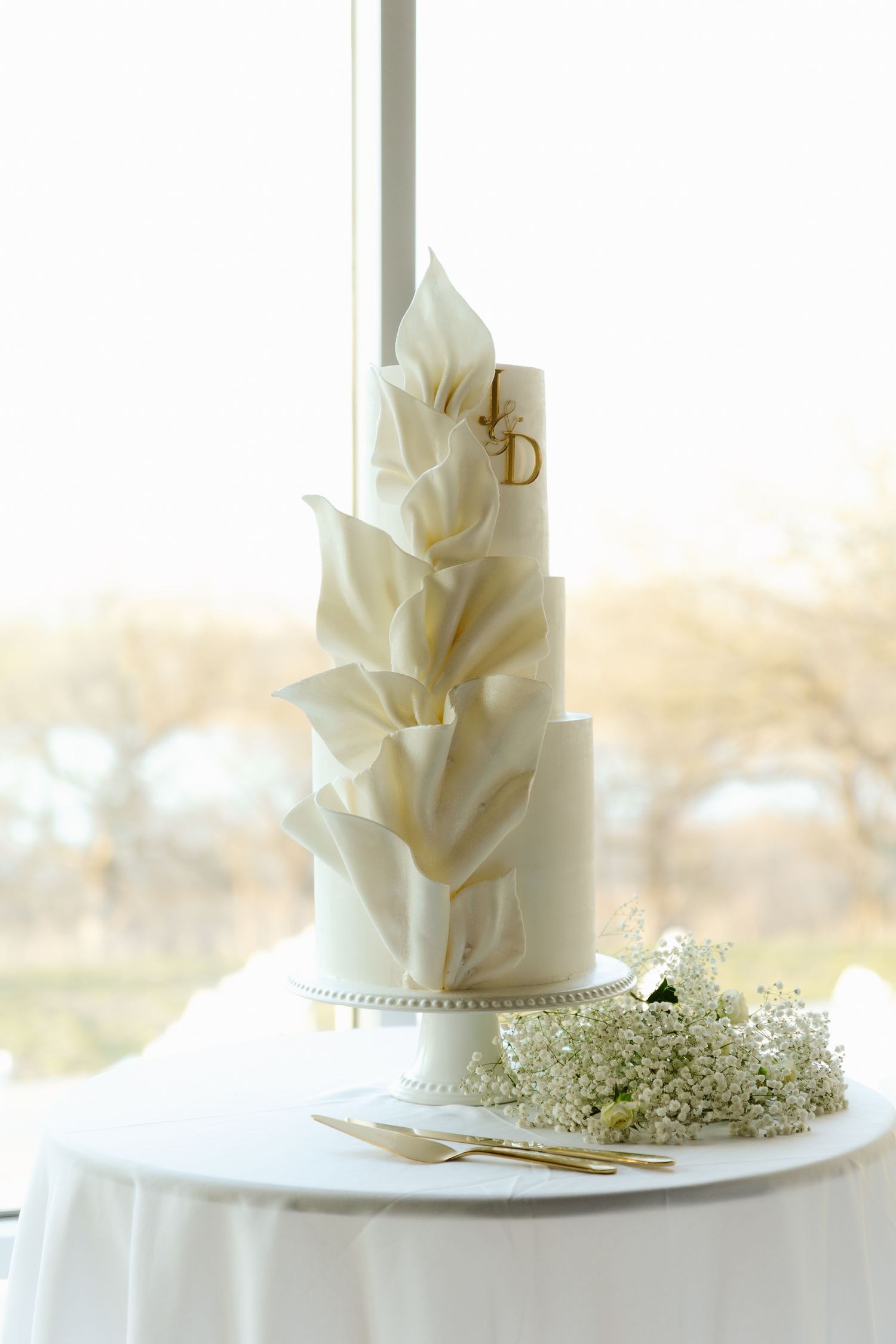 Elegant white wedding cake decorated with sugar flowers and delicate baby's breath on a simple white linen table.