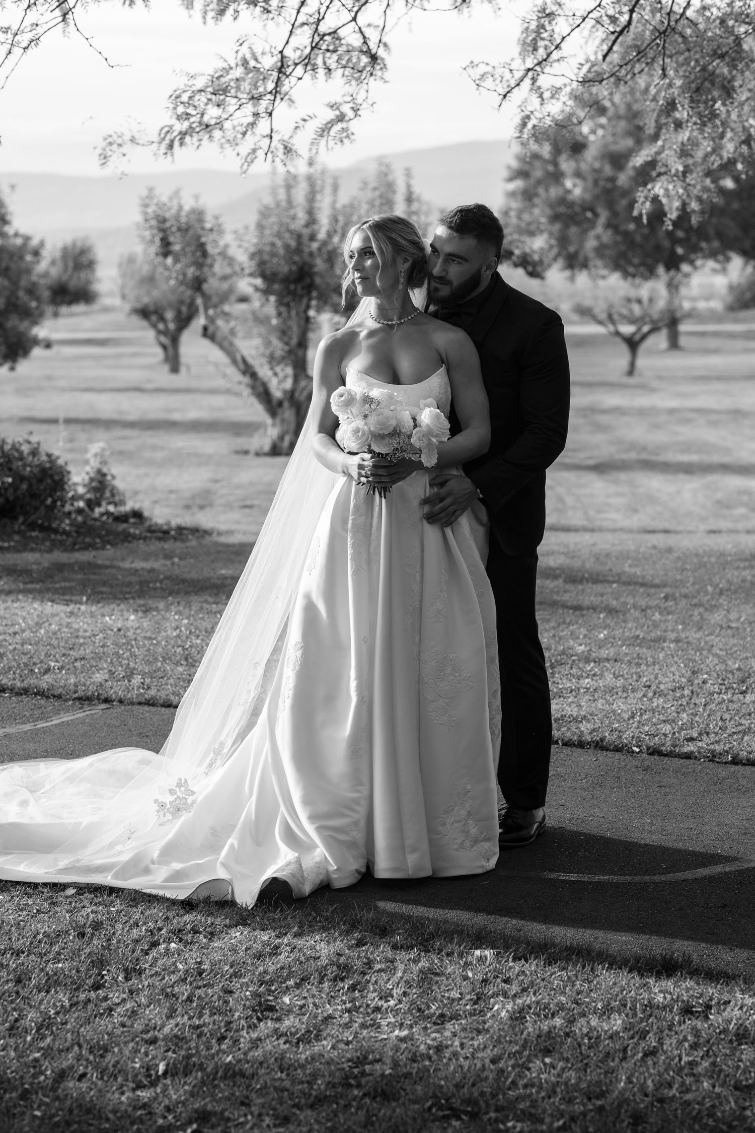 A romantic black and white photo series of a couple in wedding attire sharing intimate moments in an outdoor setting.