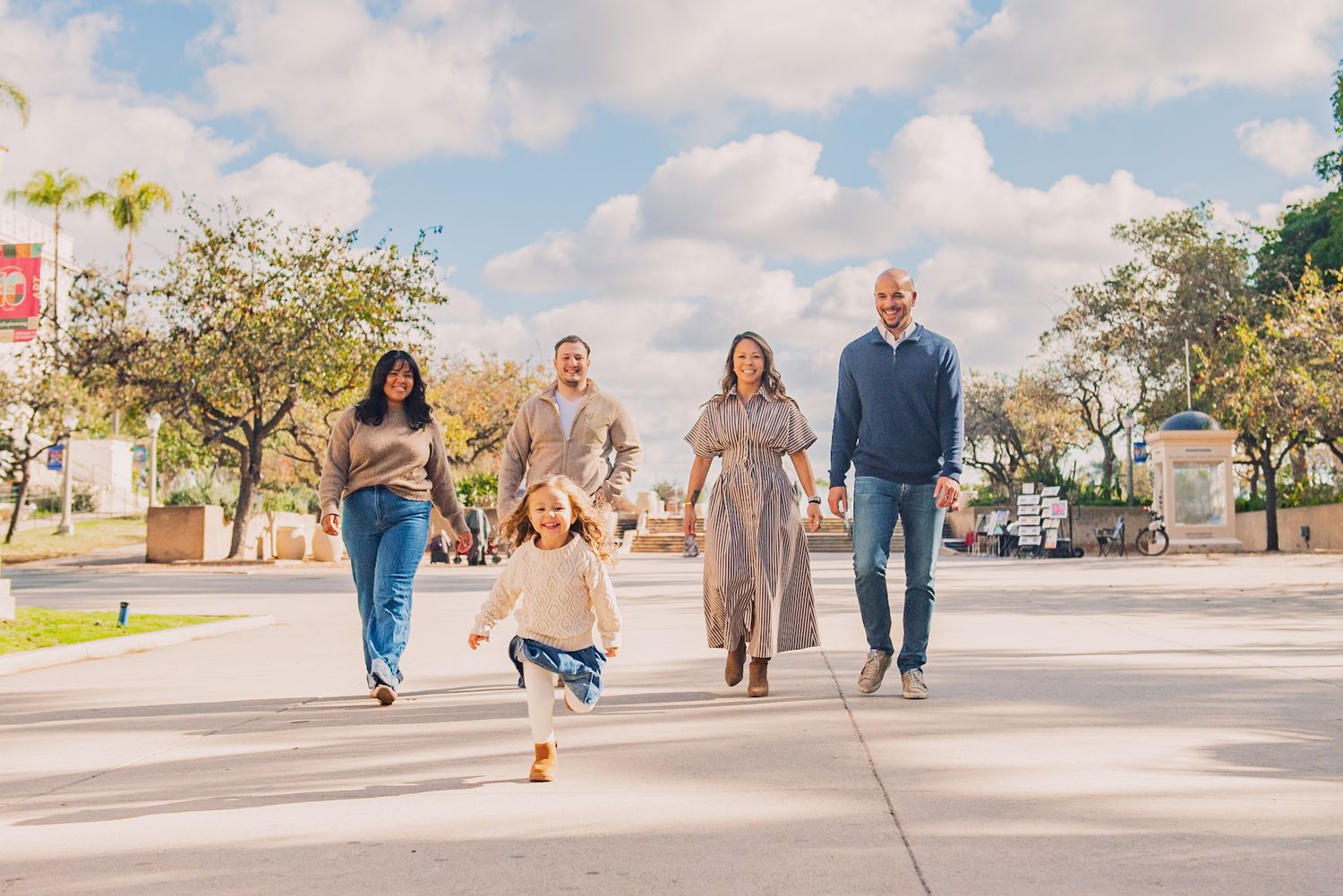People walking and playing together outdoors on a sunny day in a suburban neighborhood setting.
