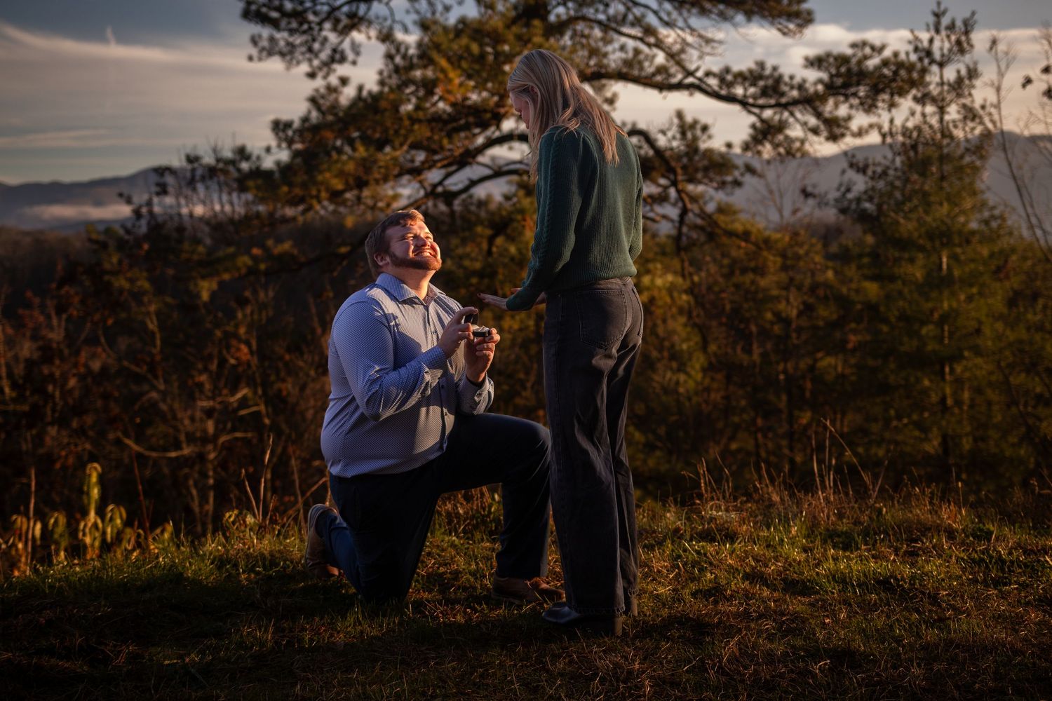 A couple embraces during a romantic sunset engagement photoshoot in a scenic outdoor setting.