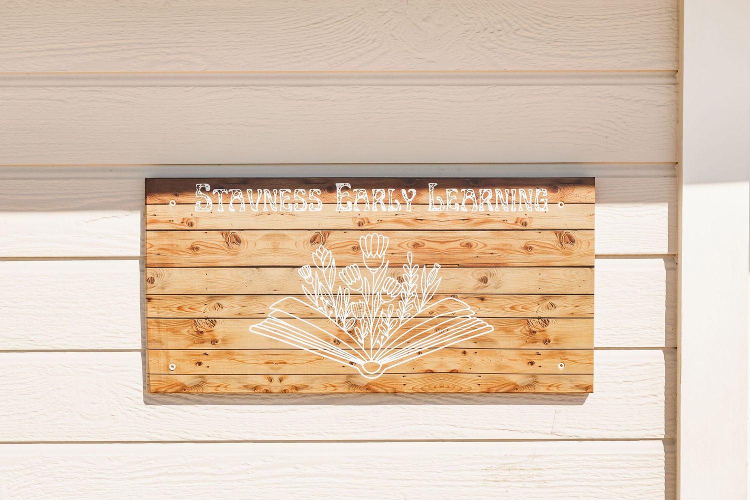Rustic wooden sign with white text mounted on a white wall features farmhouse-style decor.