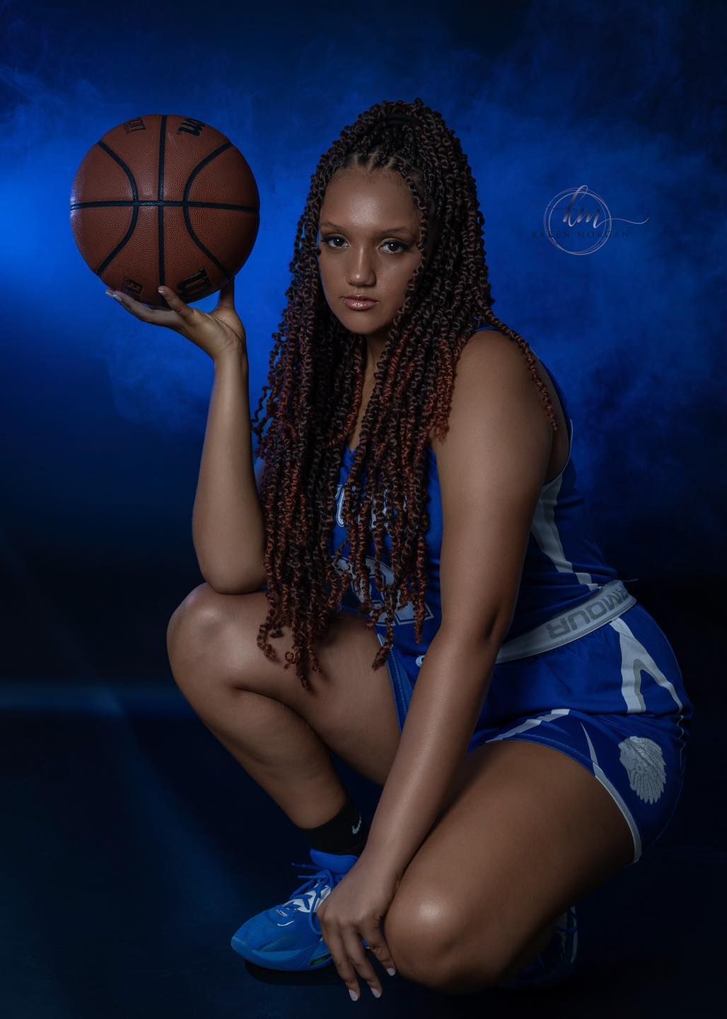 Basketball player poses in dramatic lighting against dark blue background with ball held in various positions.