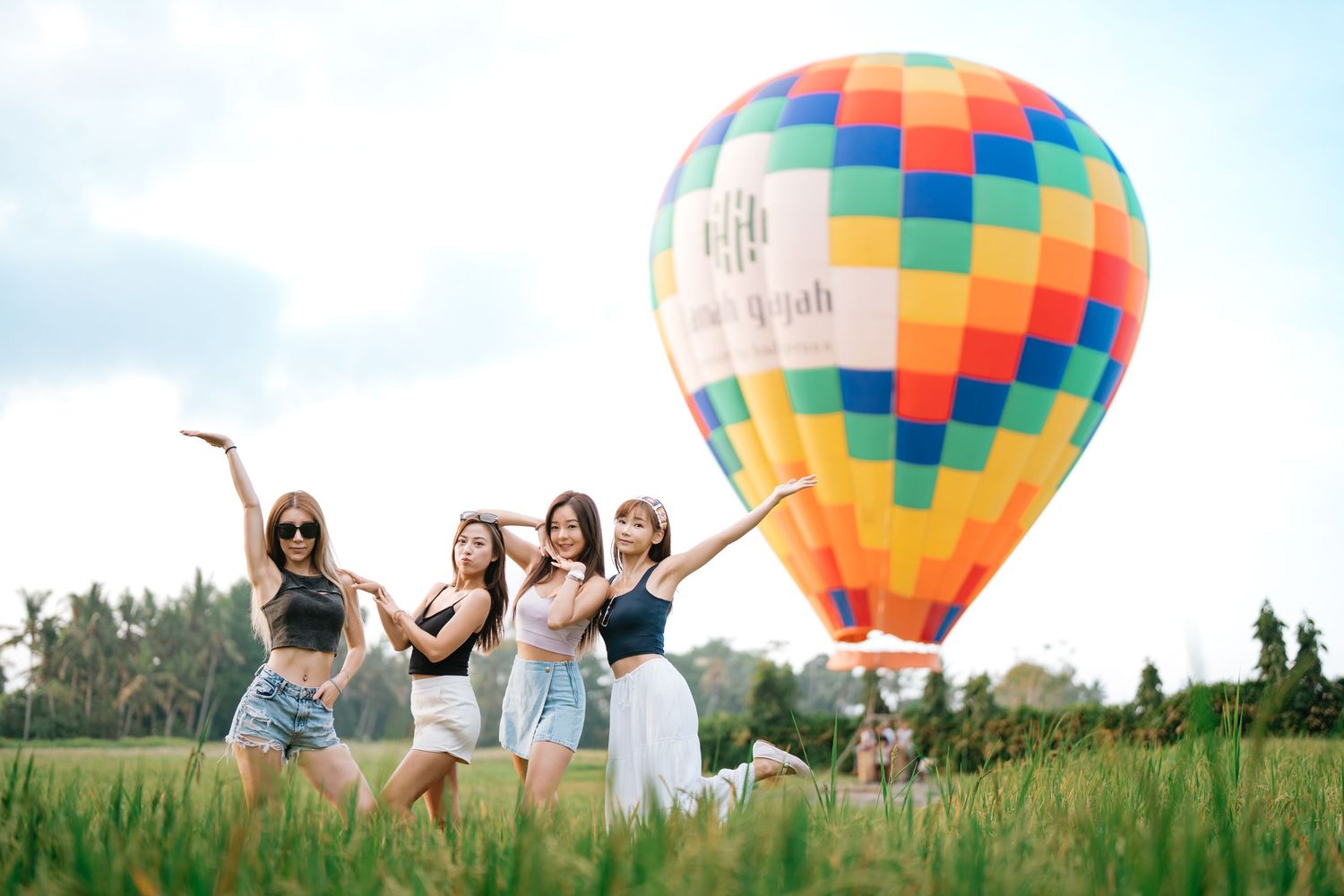 Group gathered in a field with a colorful hot air balloon in the background.