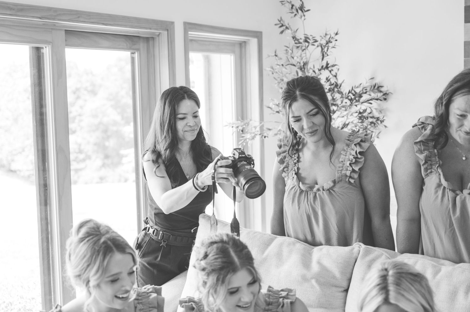A wedding preparation scene in black and white shows people gathered in a sunny room near windows and a Christmas tree.