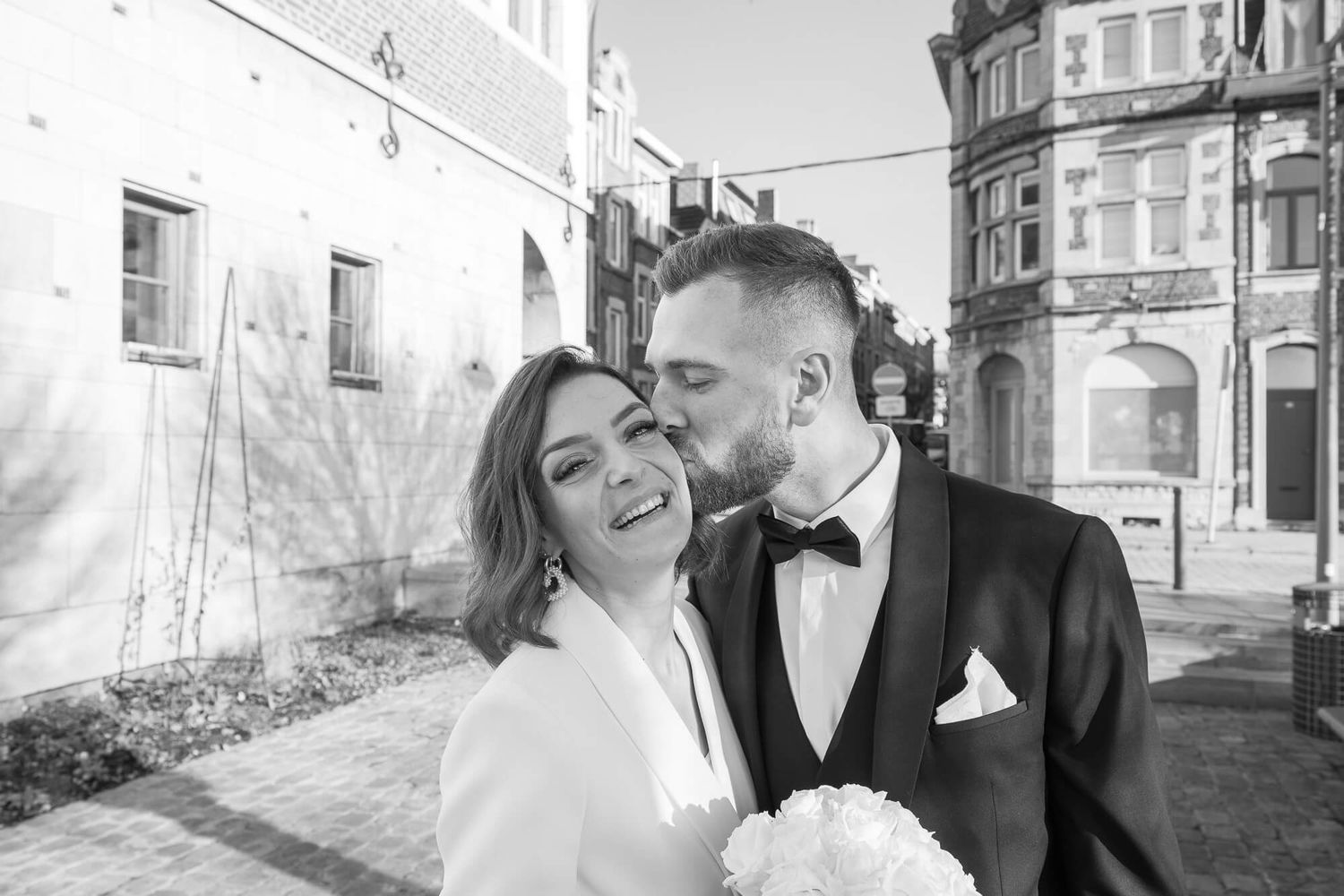 A happy couple shares a tender moment on their wedding day at an outdoor venue.