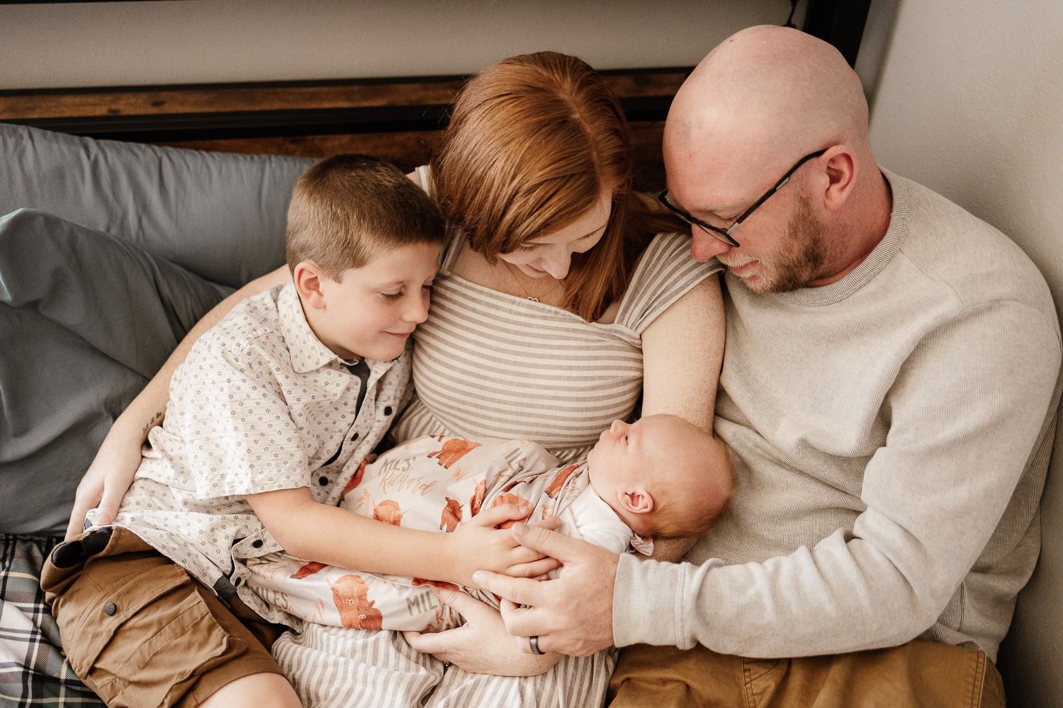 A family of four cuddles their new baby at their in-home newborn photoshoot in San Jose