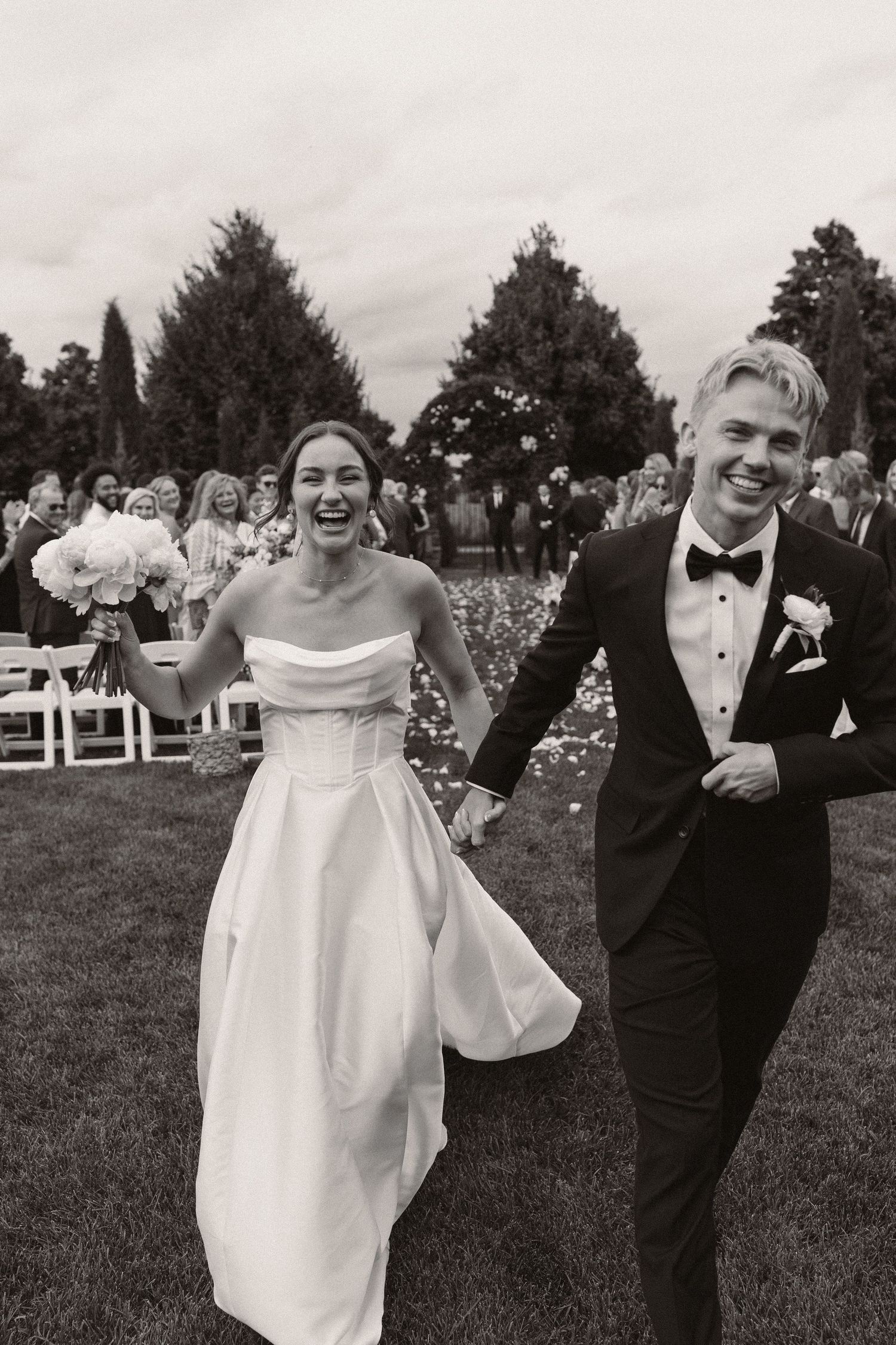 Joyful wedding celebration with confetti on an outdoor lawn with white chairs.