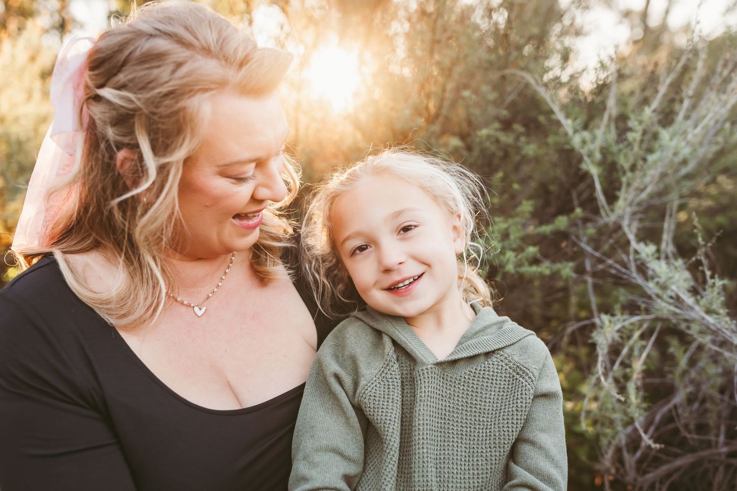 A parent and child share joyful moments together outdoors during golden hour sunset.