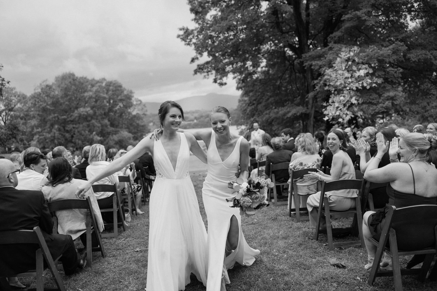 Wedding guests gather outdoors under trees for an intimate ceremony.