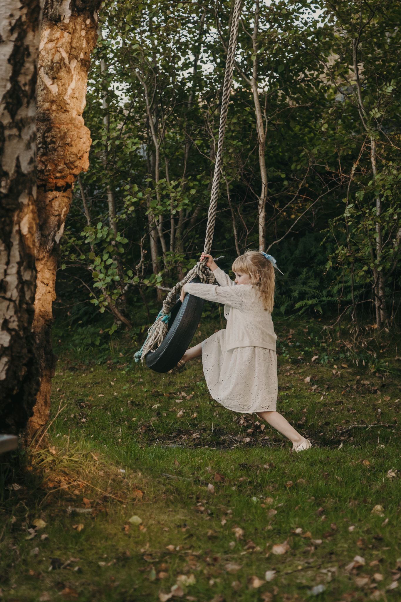 A hammock swings gently between trees in a serene forest setting during golden hour.
