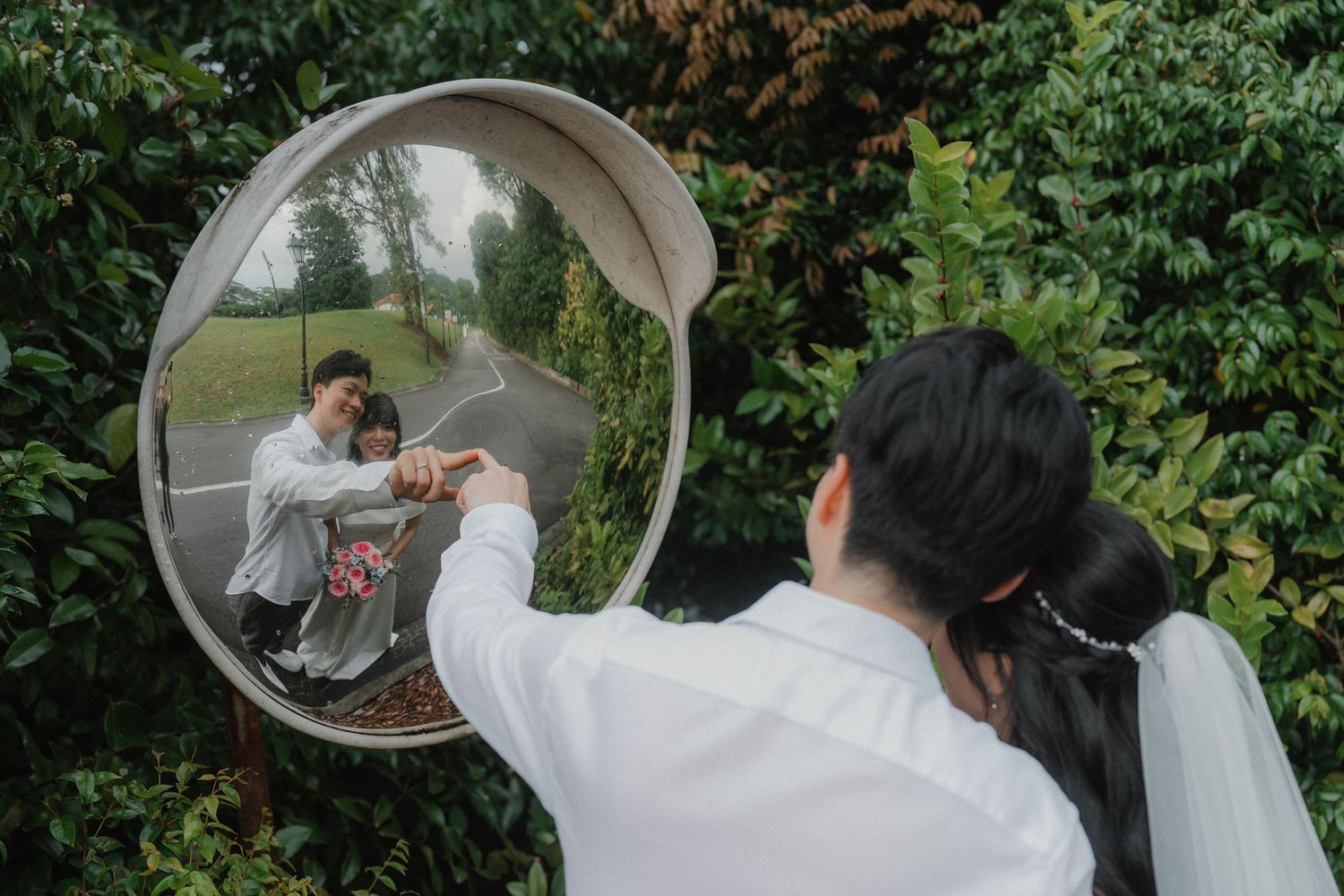 Two people share an intimate moment under a clear bubble umbrella during a romantic outdoor photoshoot.