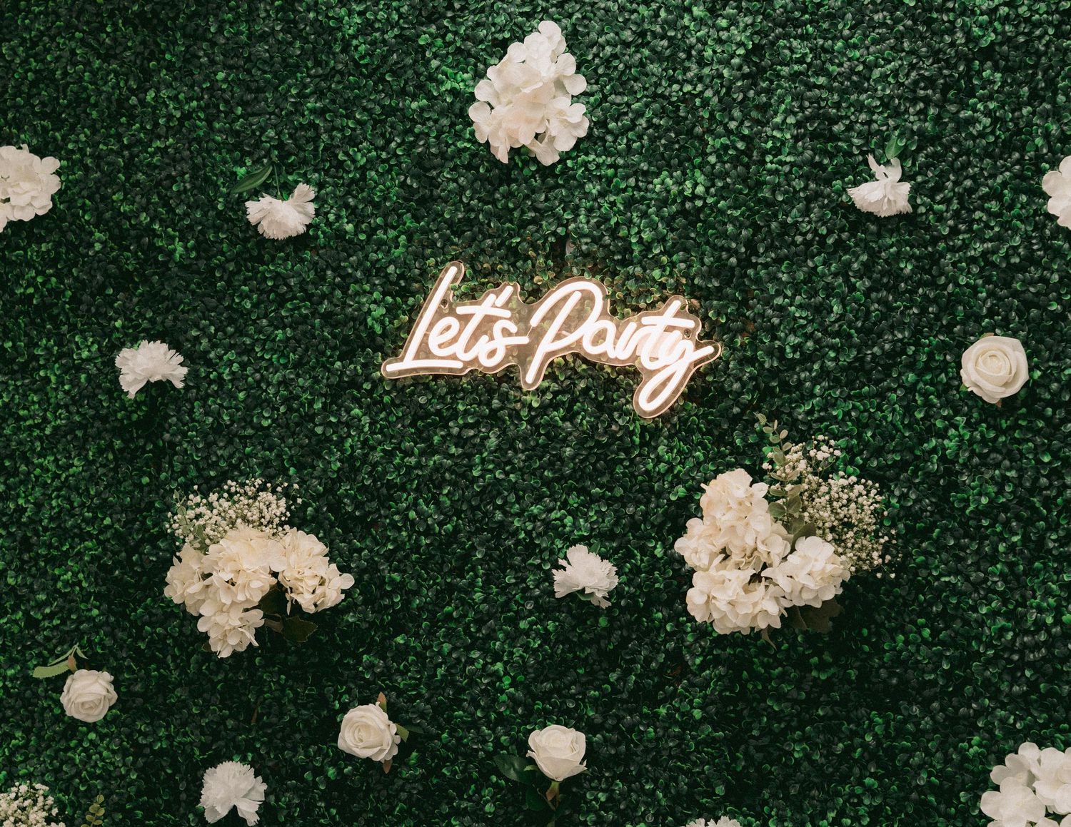 Lush green floral wall — for romantic wedding portraits in Texas with a lets party welcoming message.