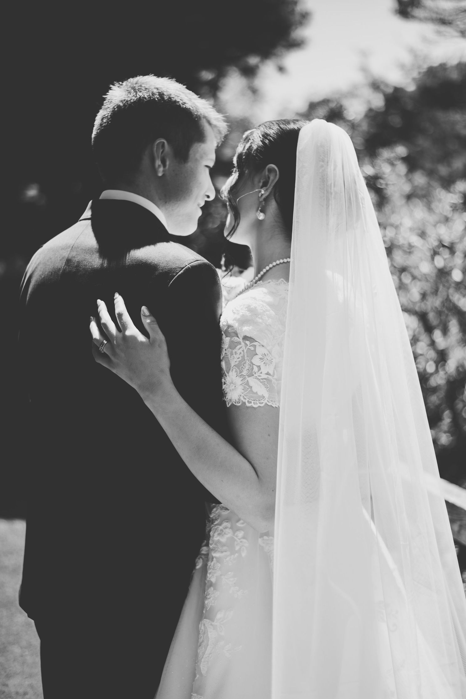 Romantic black and white wedding photography series showing tender moments between newlyweds with flowing bridal veil.
